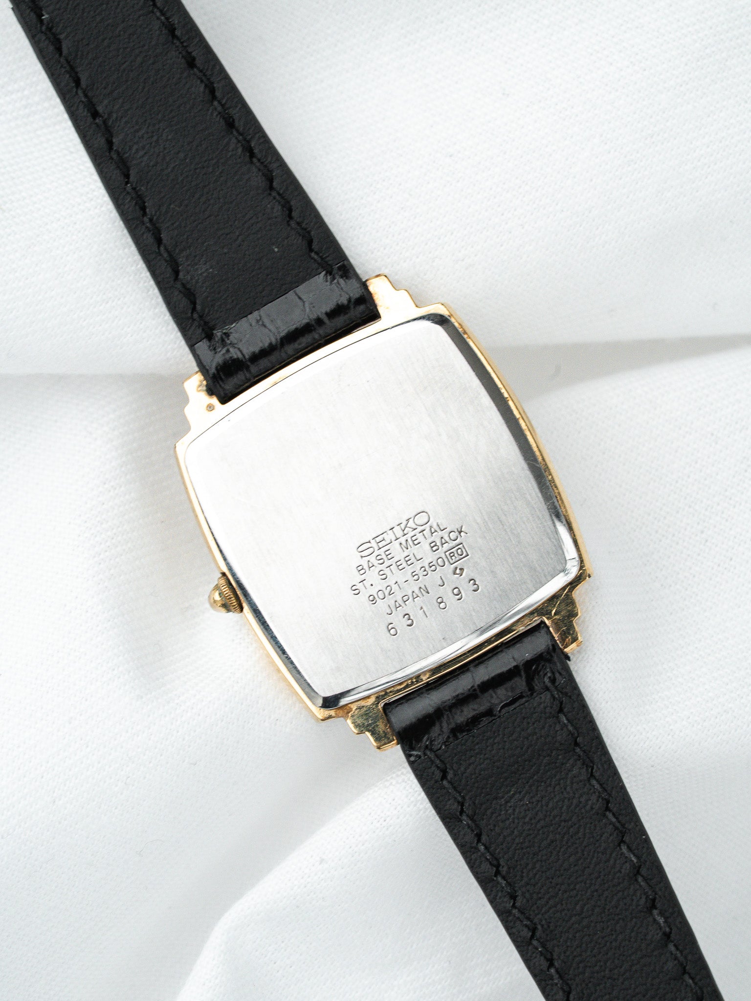 Seiko vintage watch with gold-tone case, black leather strap, steel back engraved details