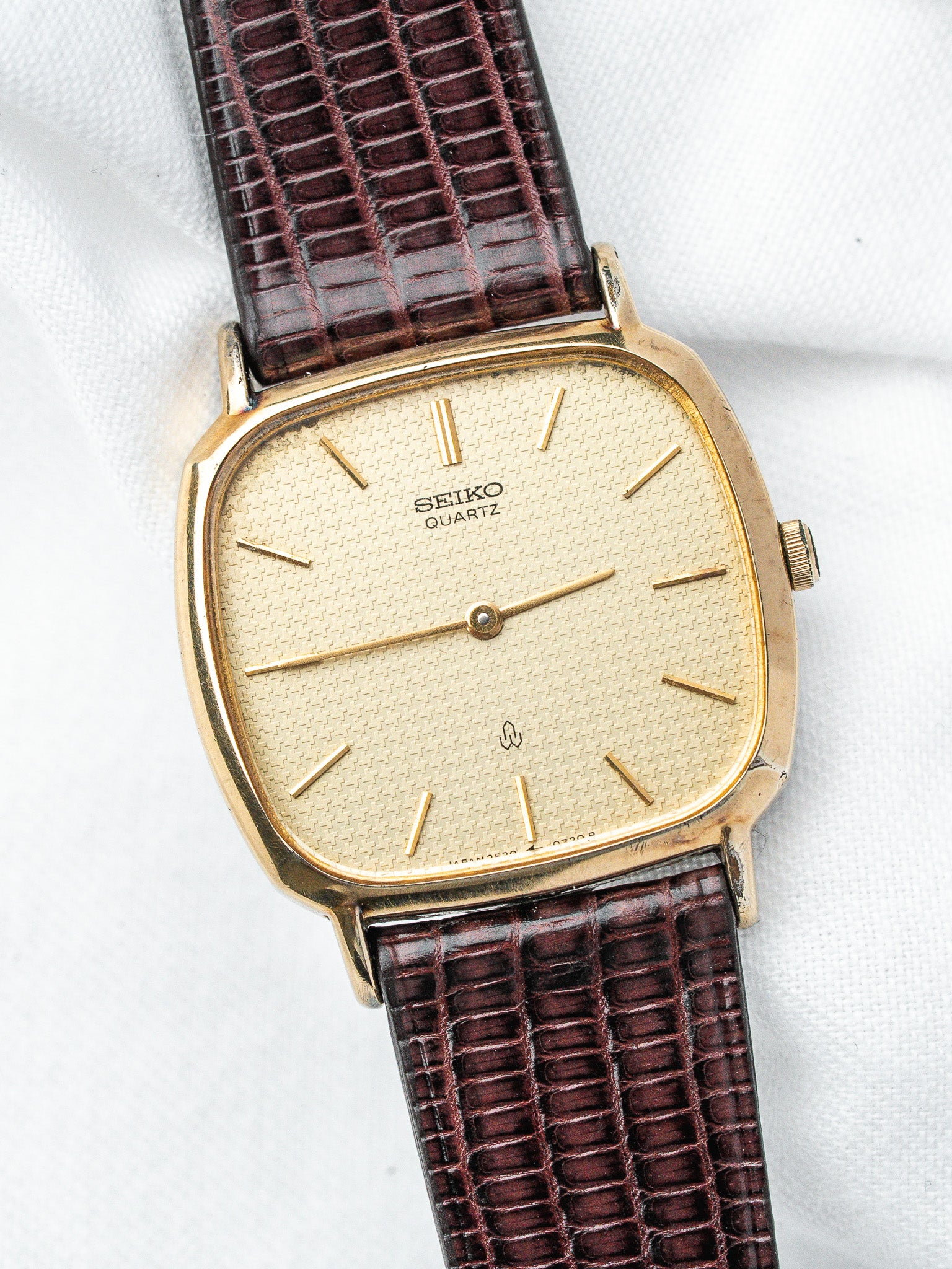 Seiko Quartz vintage watch with gold case, textured dial, and brown alligator strap