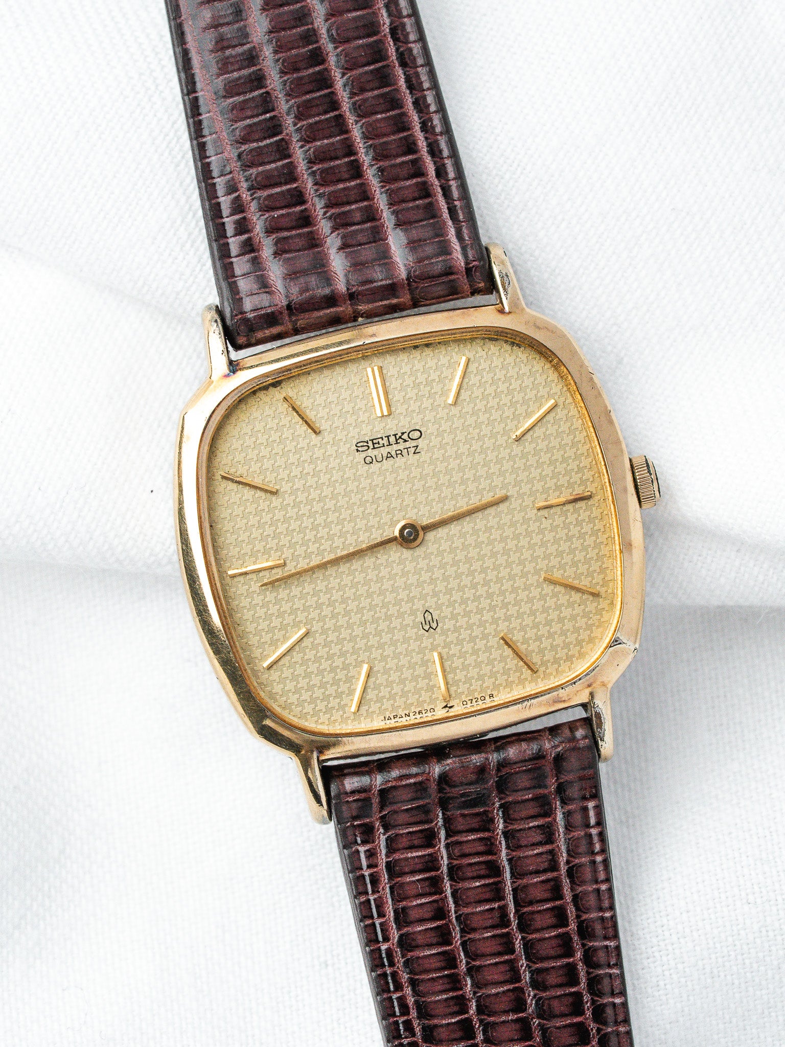 Vintage Seiko Quartz watch with gold case, textured dial, and brown lizard strap