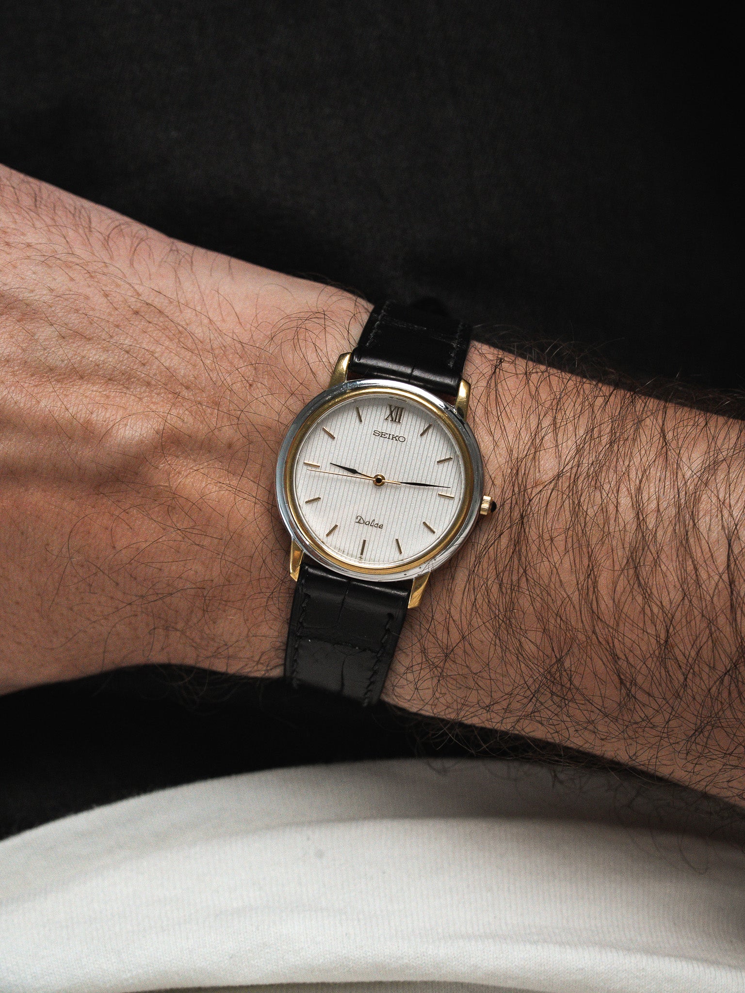 Seiko Dolce vintage watch with white dial, gold accents, black leather strap on wrist