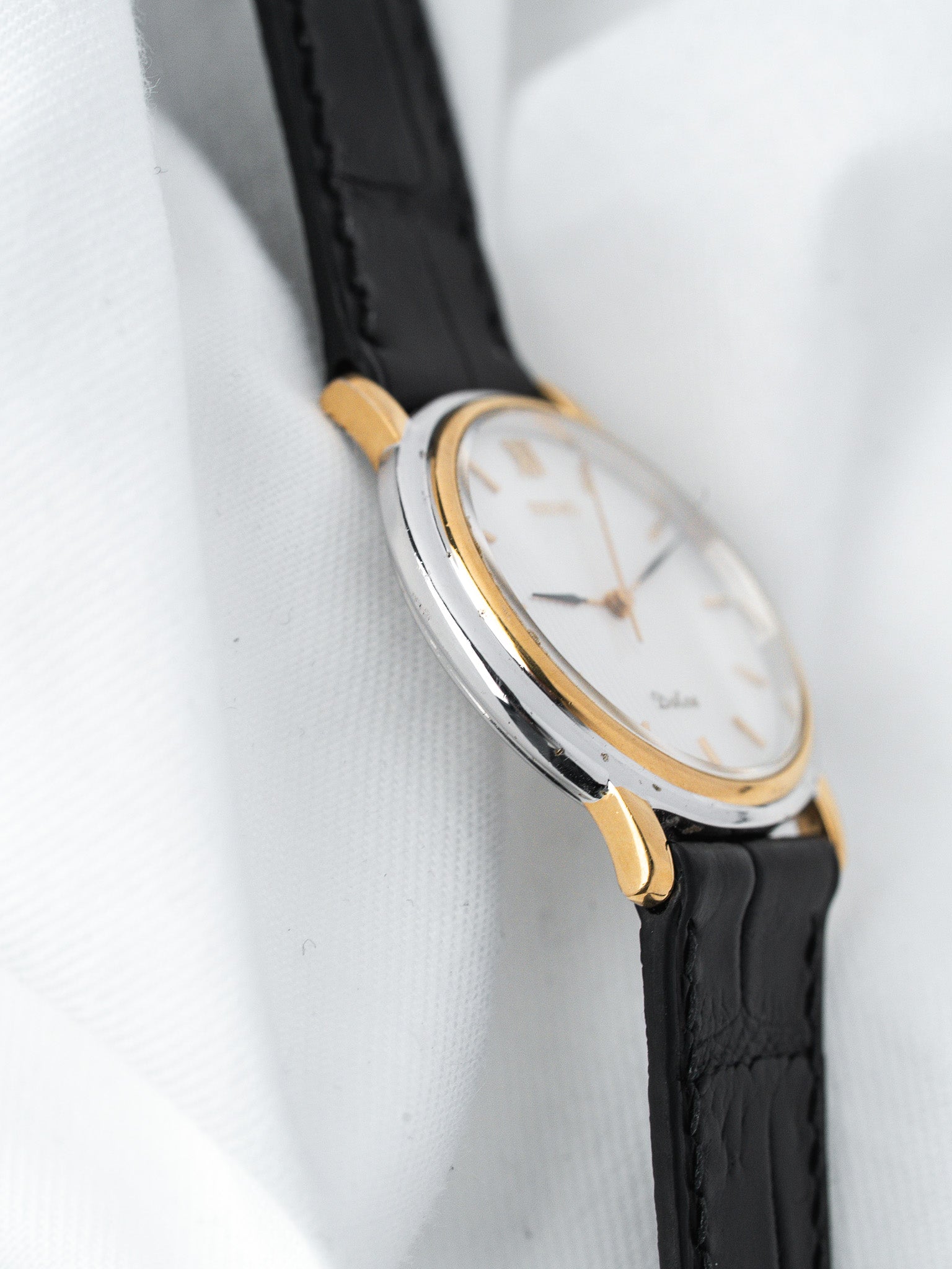 Vintage Universal Genève watch with two-tone case, white dial, black leather strap