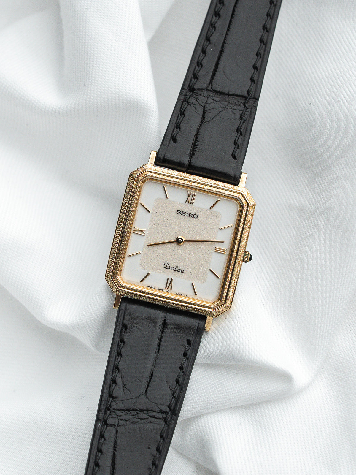 Montre Seiko Dolce vintage, boîtier rectangulaire doré, cadran blanc et bracelet cuir noir