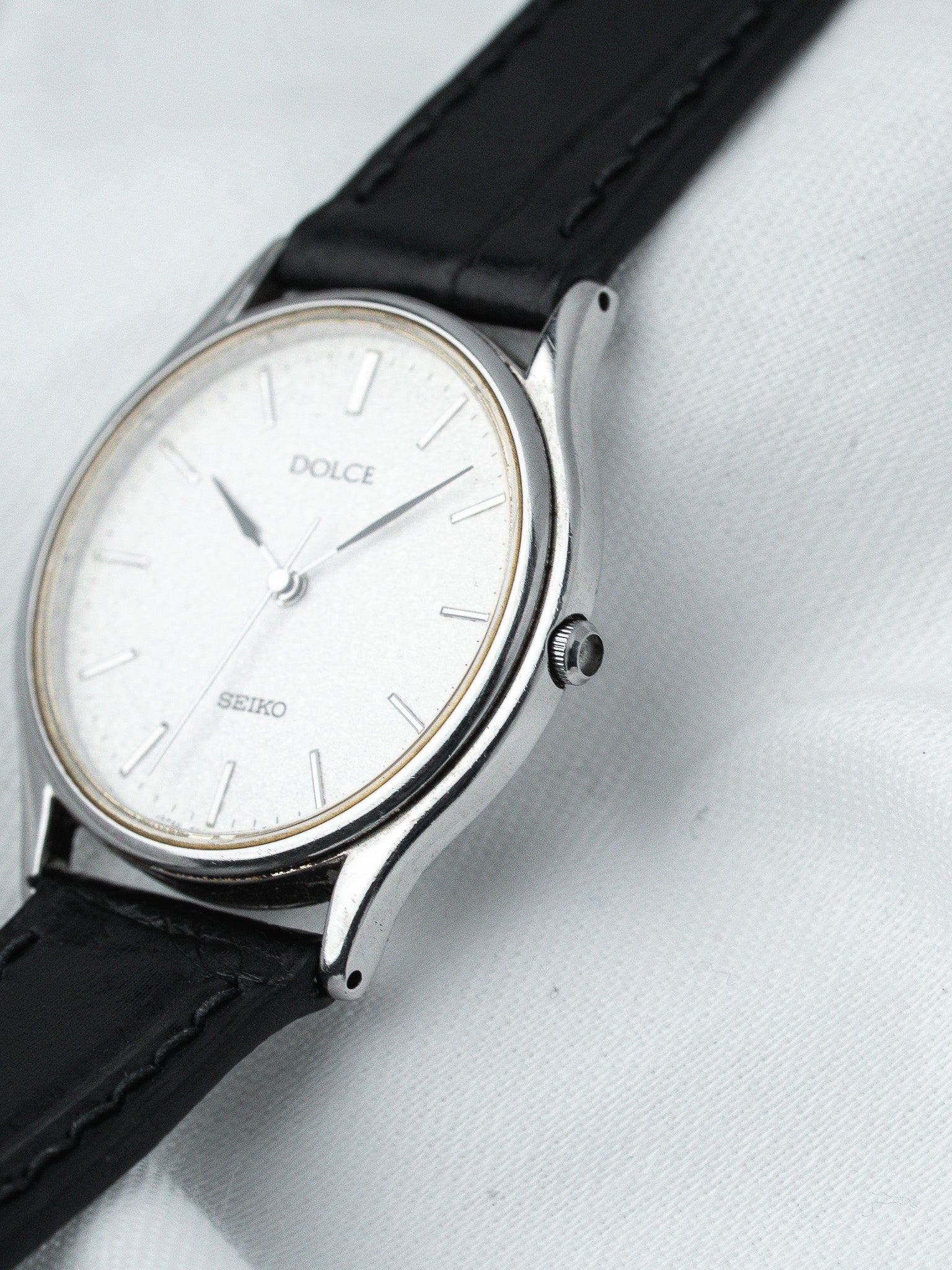 Seiko Dolce vintage watch with silver dial, black leather strap, on white fabric