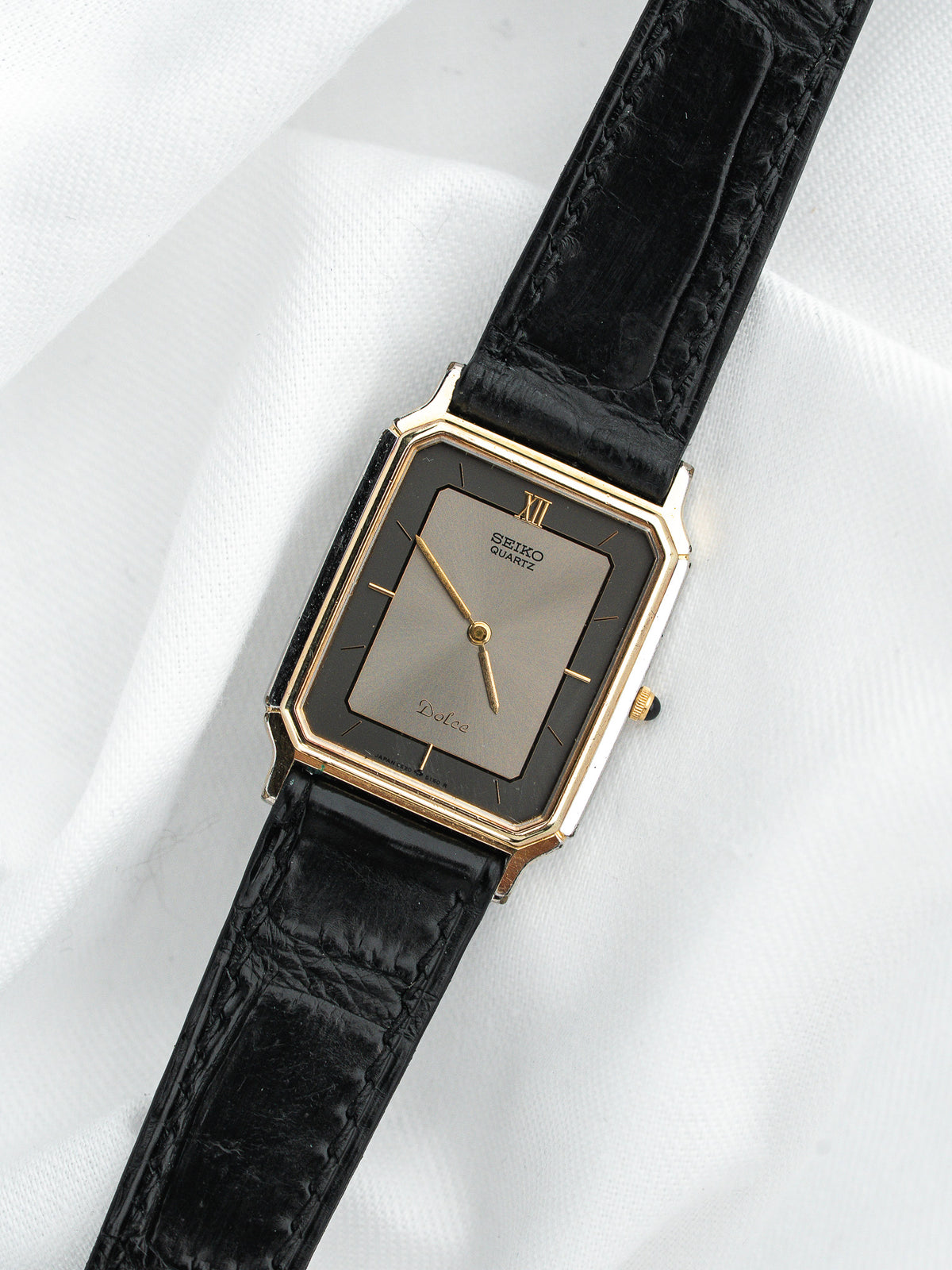Montre Seiko Dolce vintage, boîtier rectangulaire doré, cadran gris et bracelet cuir noir