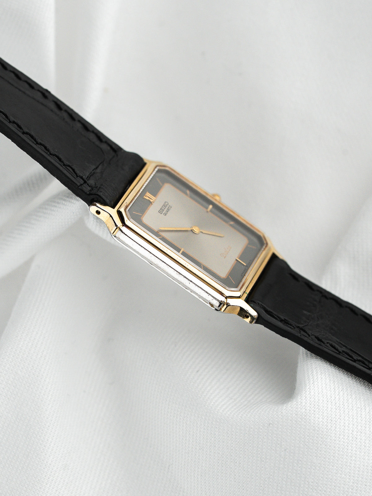 Montre Seiko vintage, boîtier rectangulaire doré, cadran champagne et bracelet cuir noir