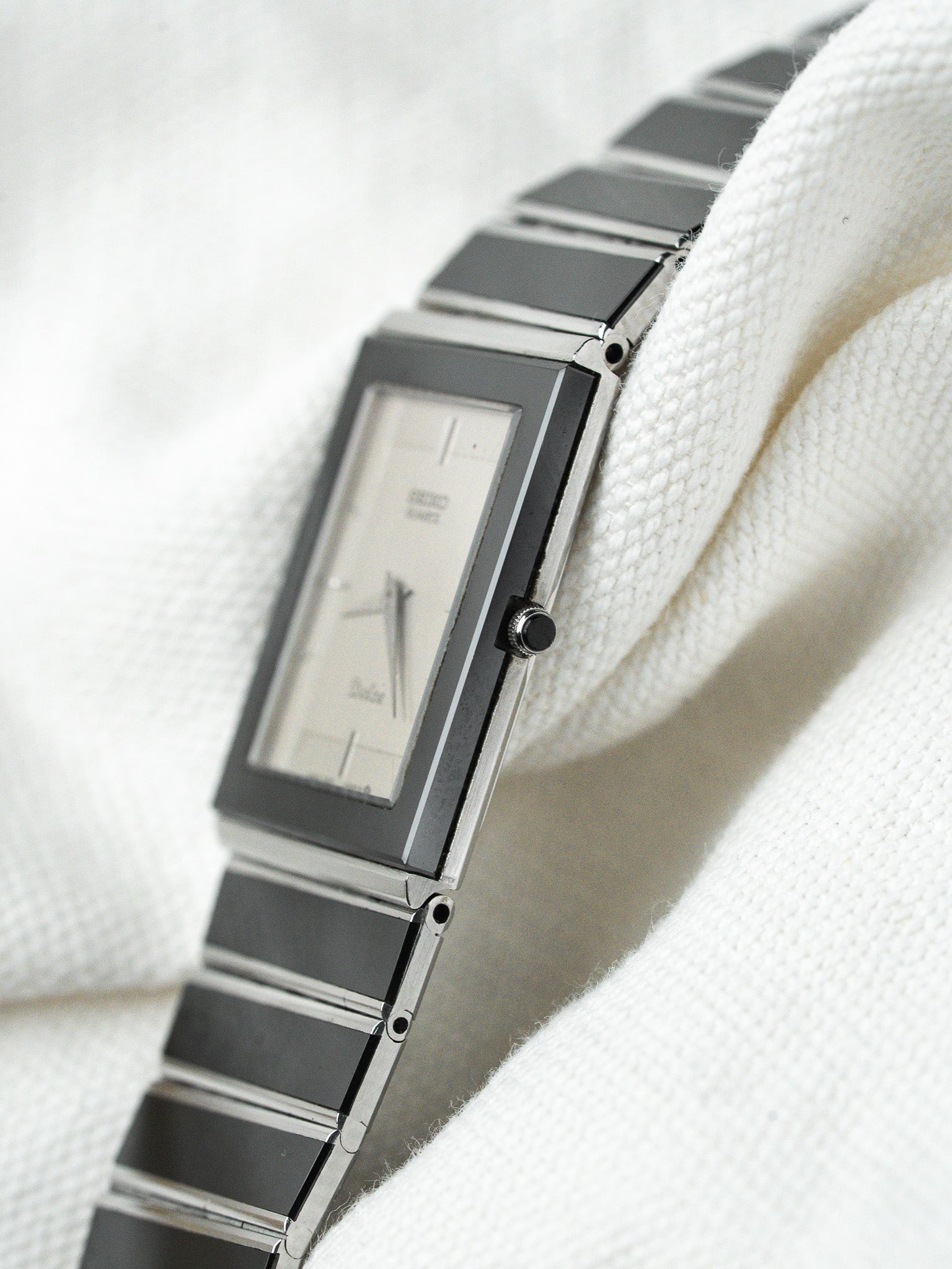 Seiko quartz vintage watch with rectangular case, silver dial, black accents, on white fabric