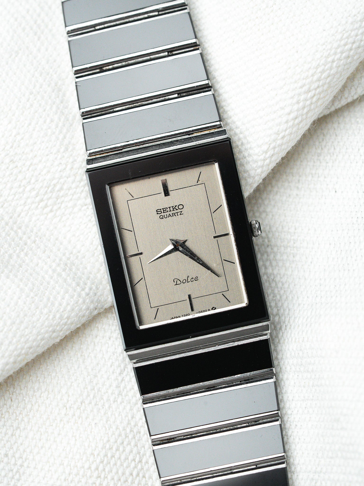 Seiko Dolce vintage quartz watch with rectangular black case and silver dial on white fabric