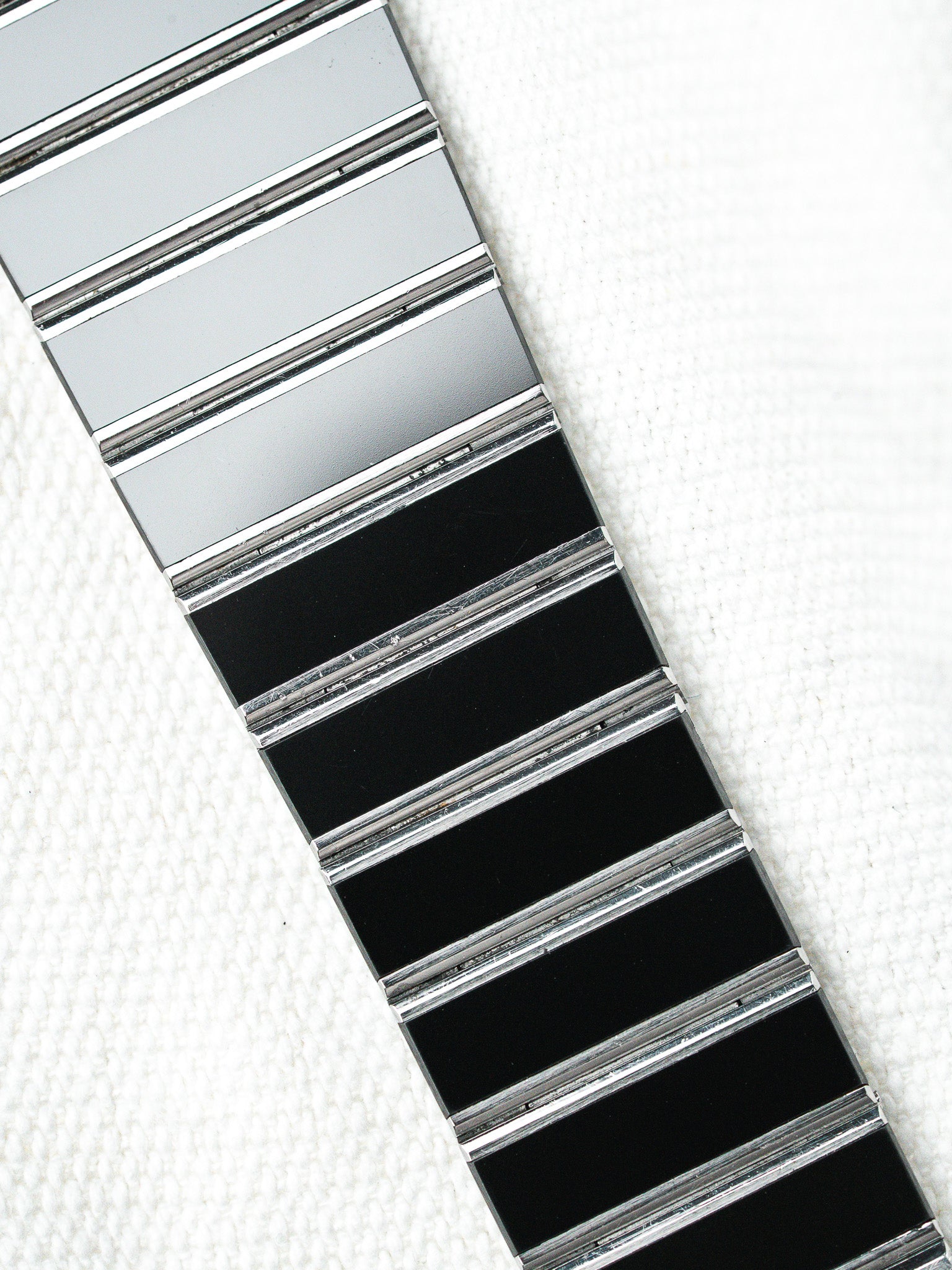 Vintage Omega Constellation bracelet with black and silver links on white textured background