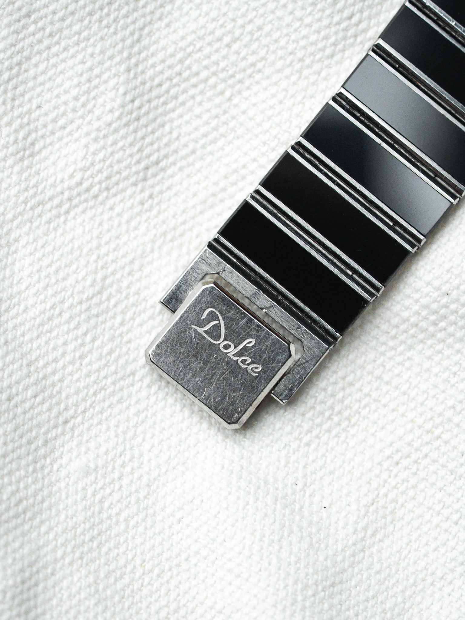 Dolce vintage watch bracelet with black enamel links and engraved clasp on white fabric