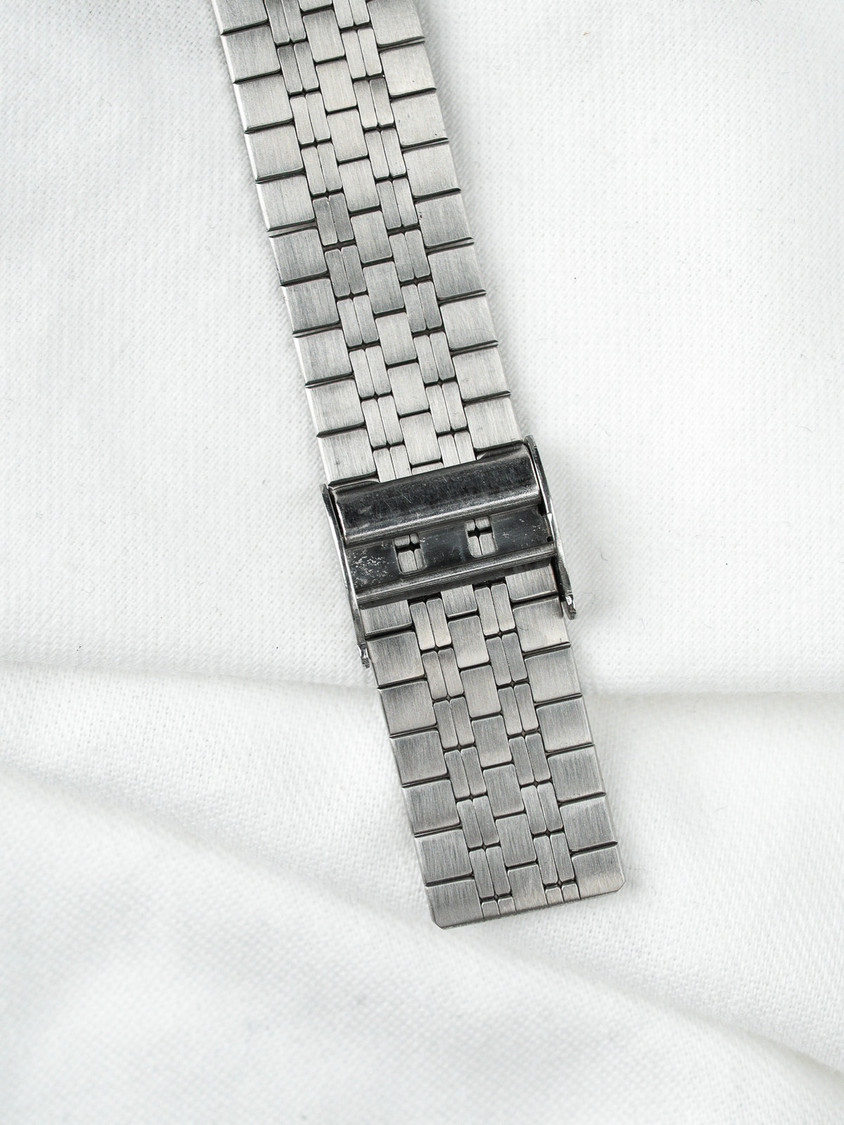 Bracelet de montre vintage en acier inoxydable avec fermoir déployant sur fond blanc
