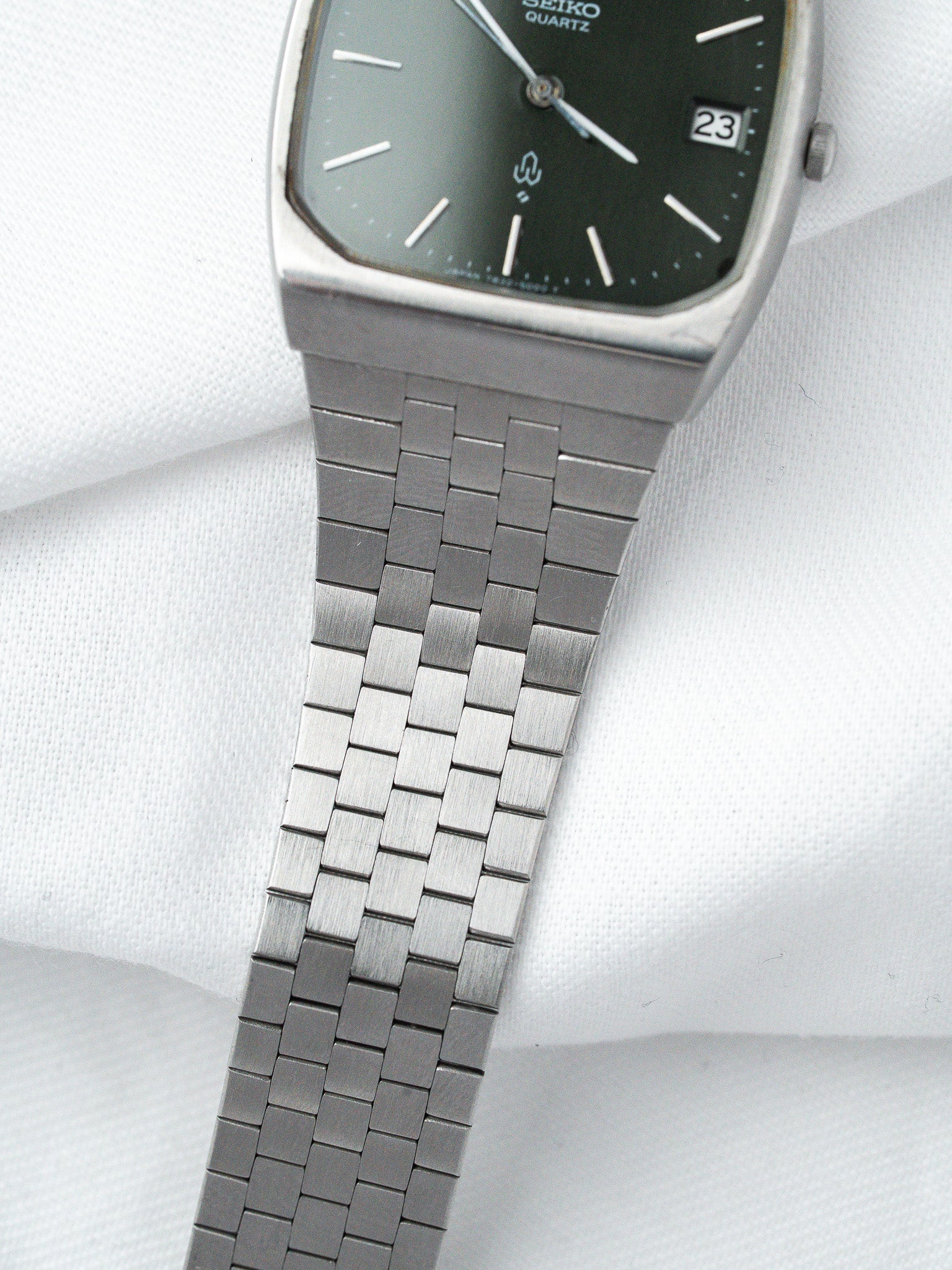 Seiko Quartz vintage watch with green dial and metal bracelet on white fabric