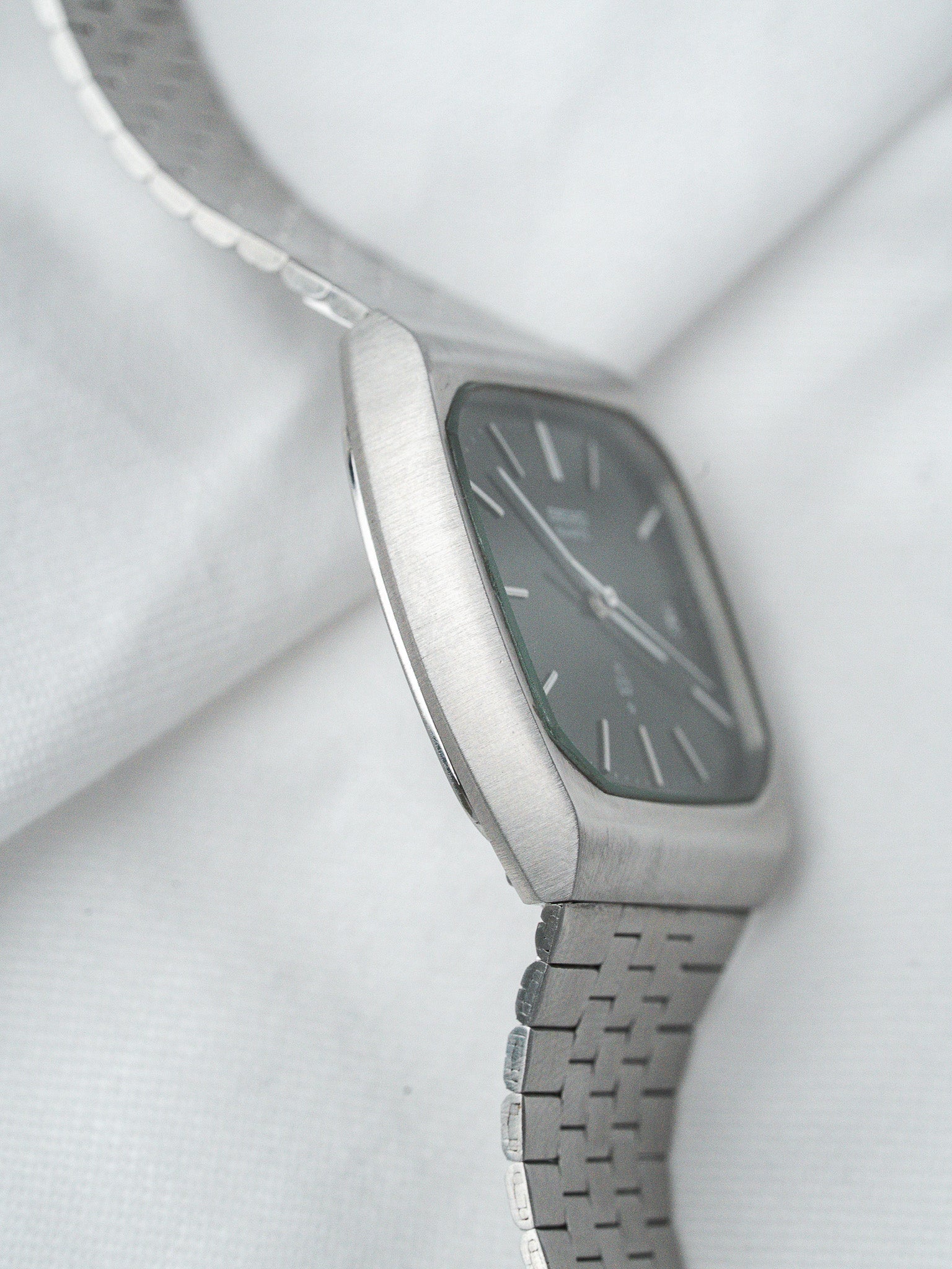 Vintage Omega watch with gray dial, brushed steel case, and integrated bracelet