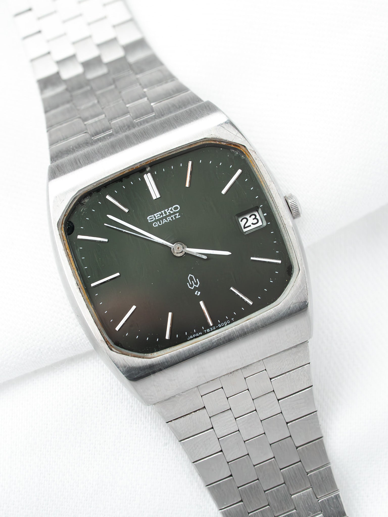 Seiko Quartz vintage watch with dark green dial, silver case, and metal bracelet on white background