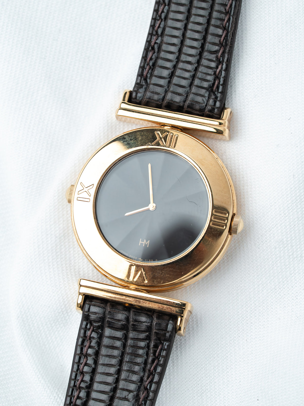 Vintage HM watch with gold case, gray dial, and black textured strap