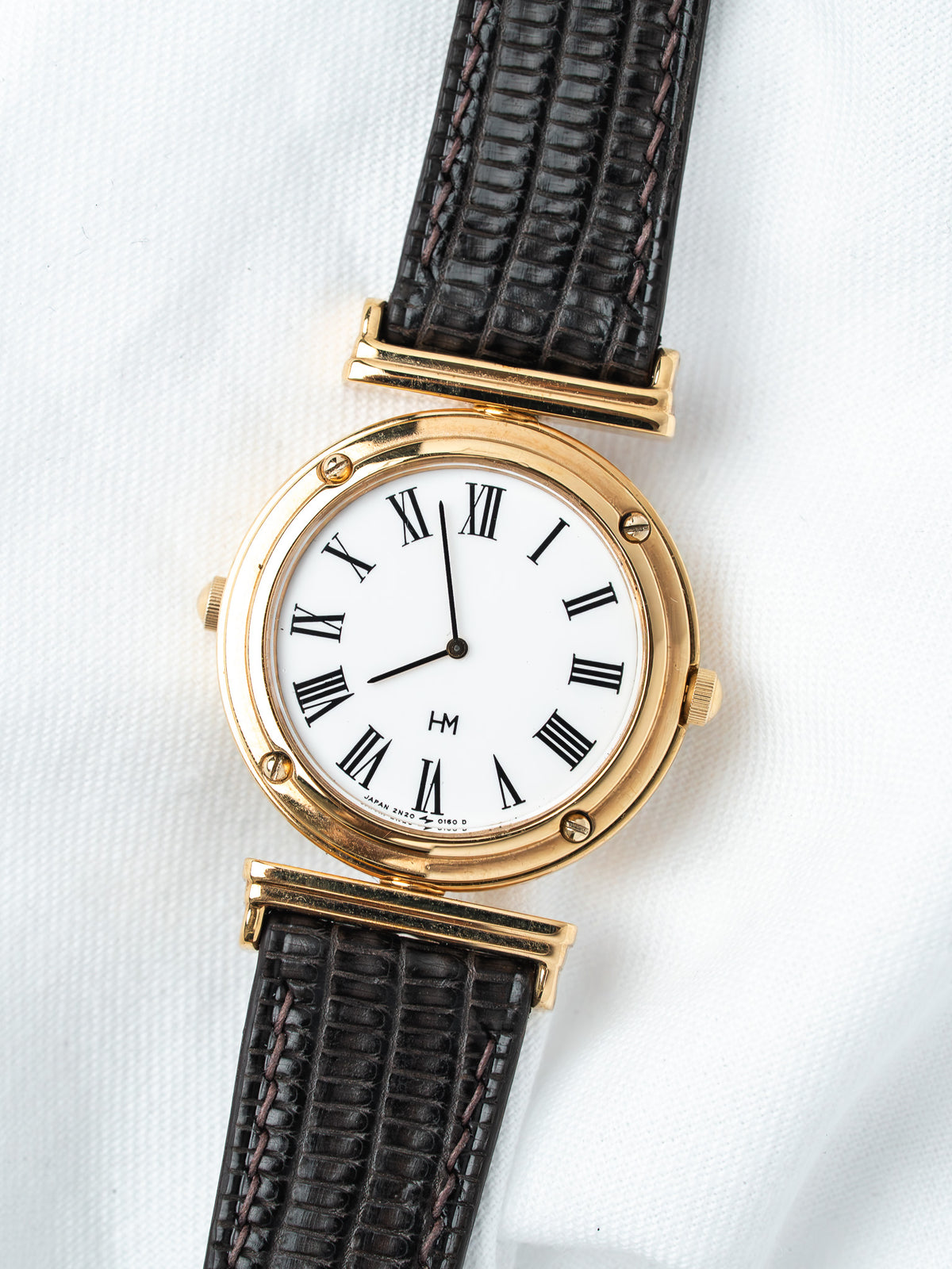 Vintage HM watch with gold case, white dial, Roman numerals, black leather strap
