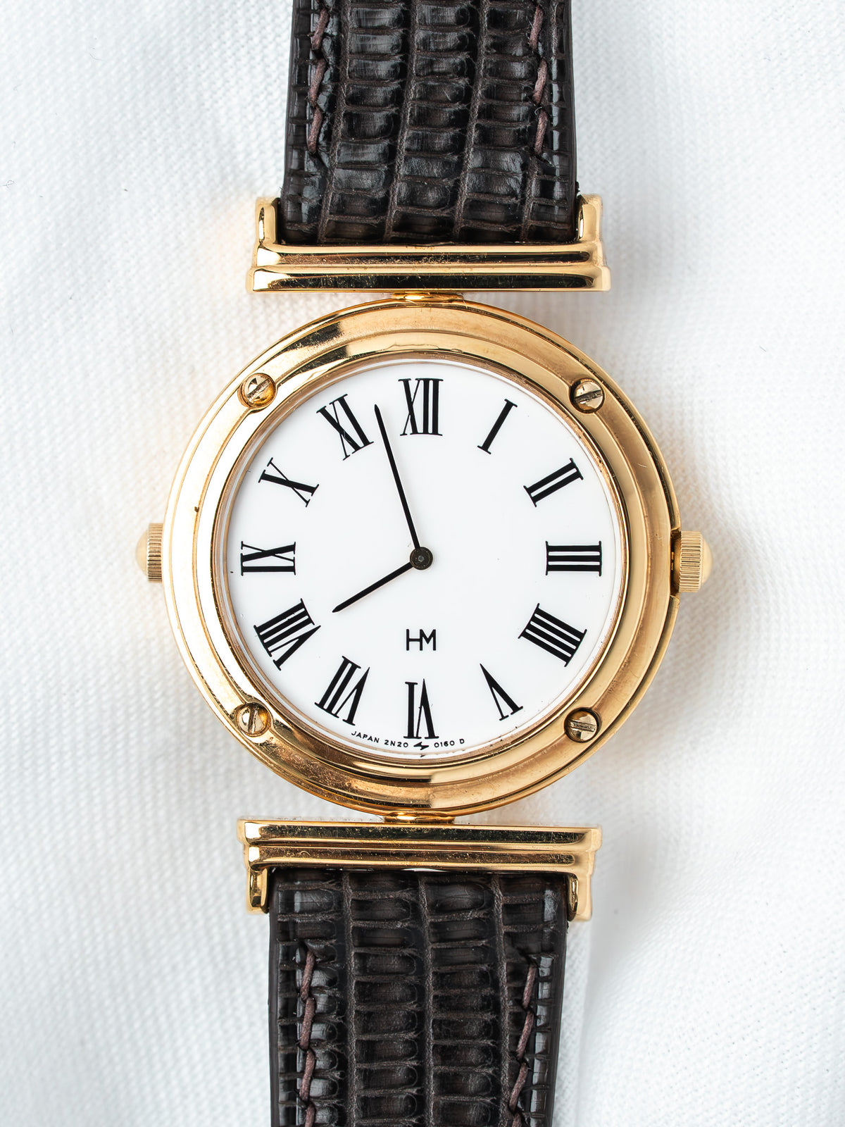 HM vintage watch with gold case, white dial, Roman numerals, black leather strap