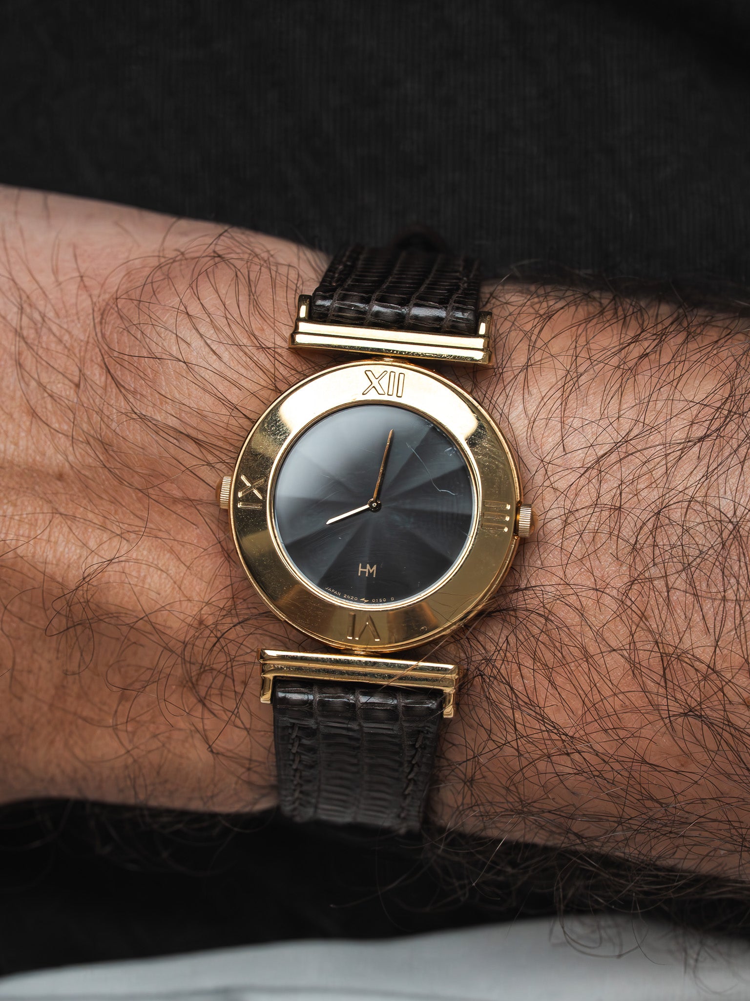 Vintage HM watch with gold case, black dial, and textured leather strap on wrist