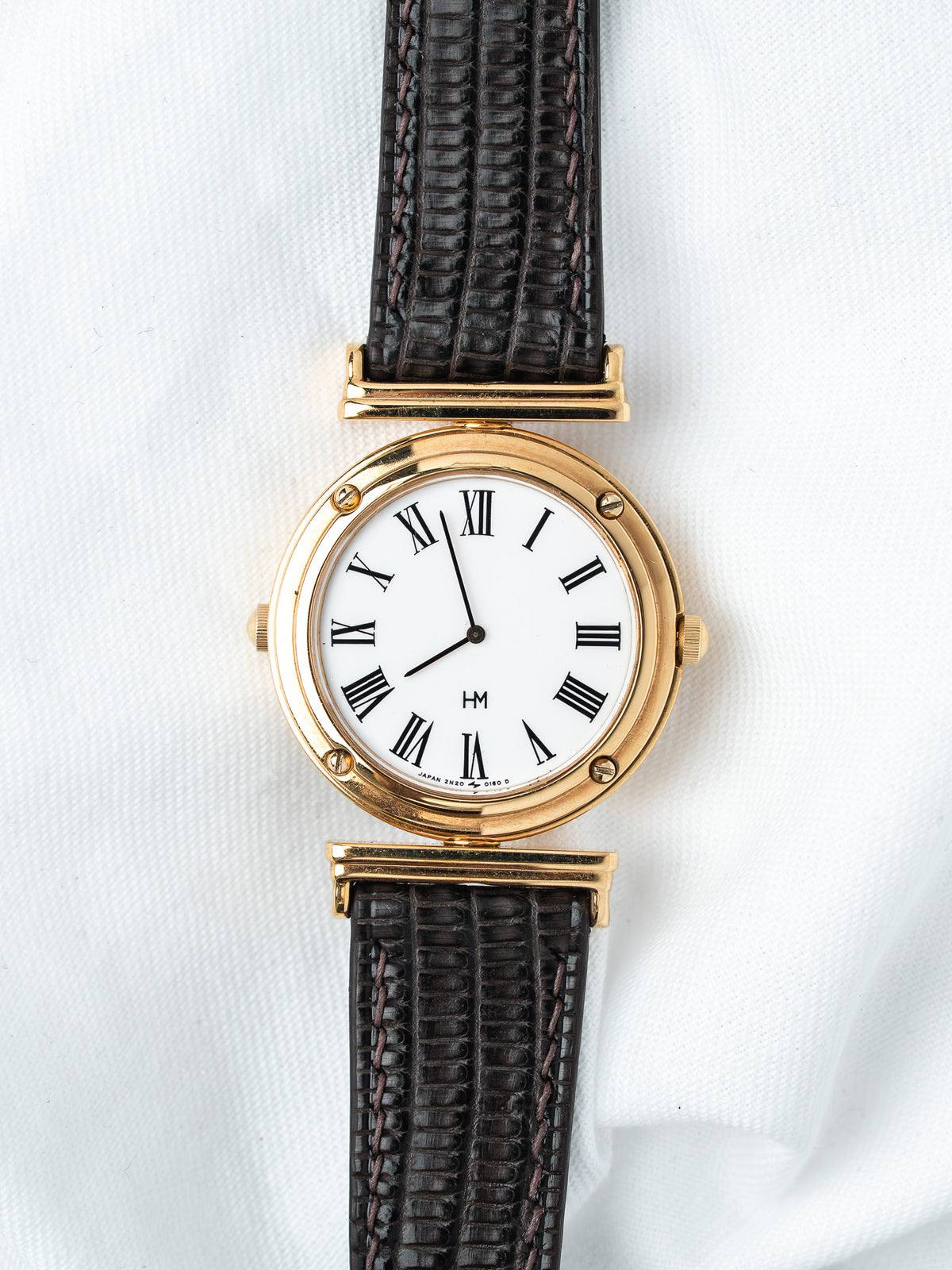 Vintage HM watch with gold case, white dial, Roman numerals, black leather strap
