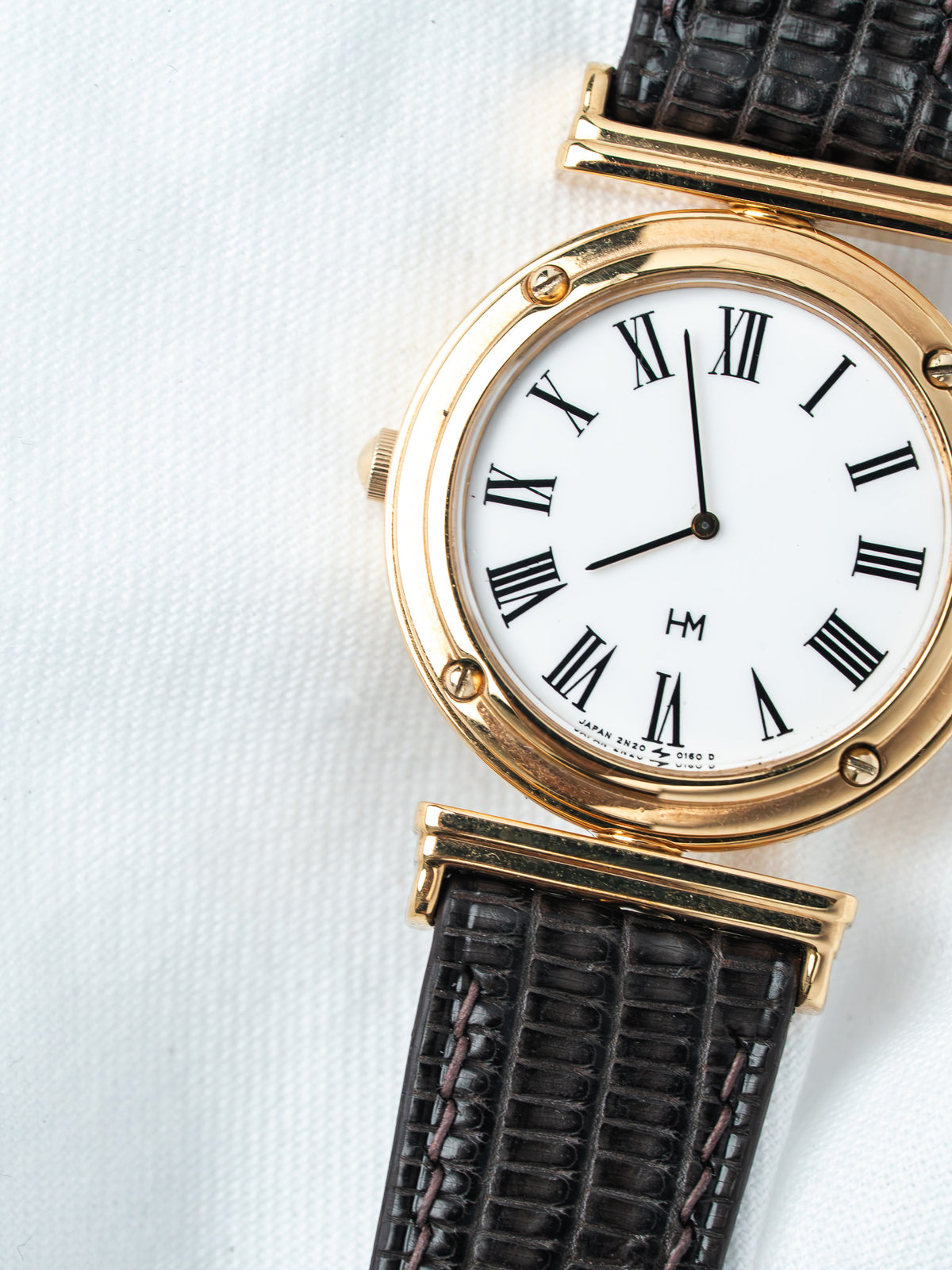 HM vintage watch with gold case, white dial, Roman numerals, black leather strap