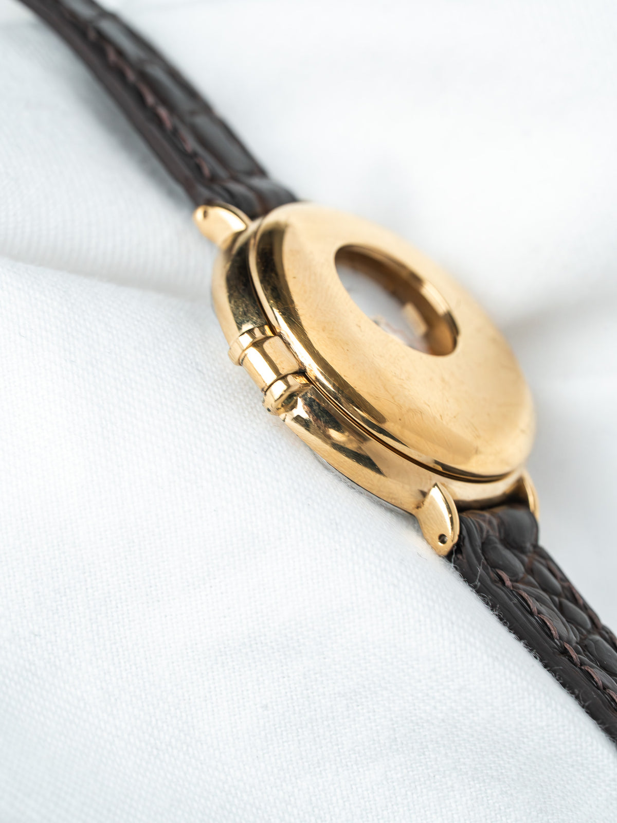 Vintage Cartier watch with gold case and brown alligator strap on white fabric