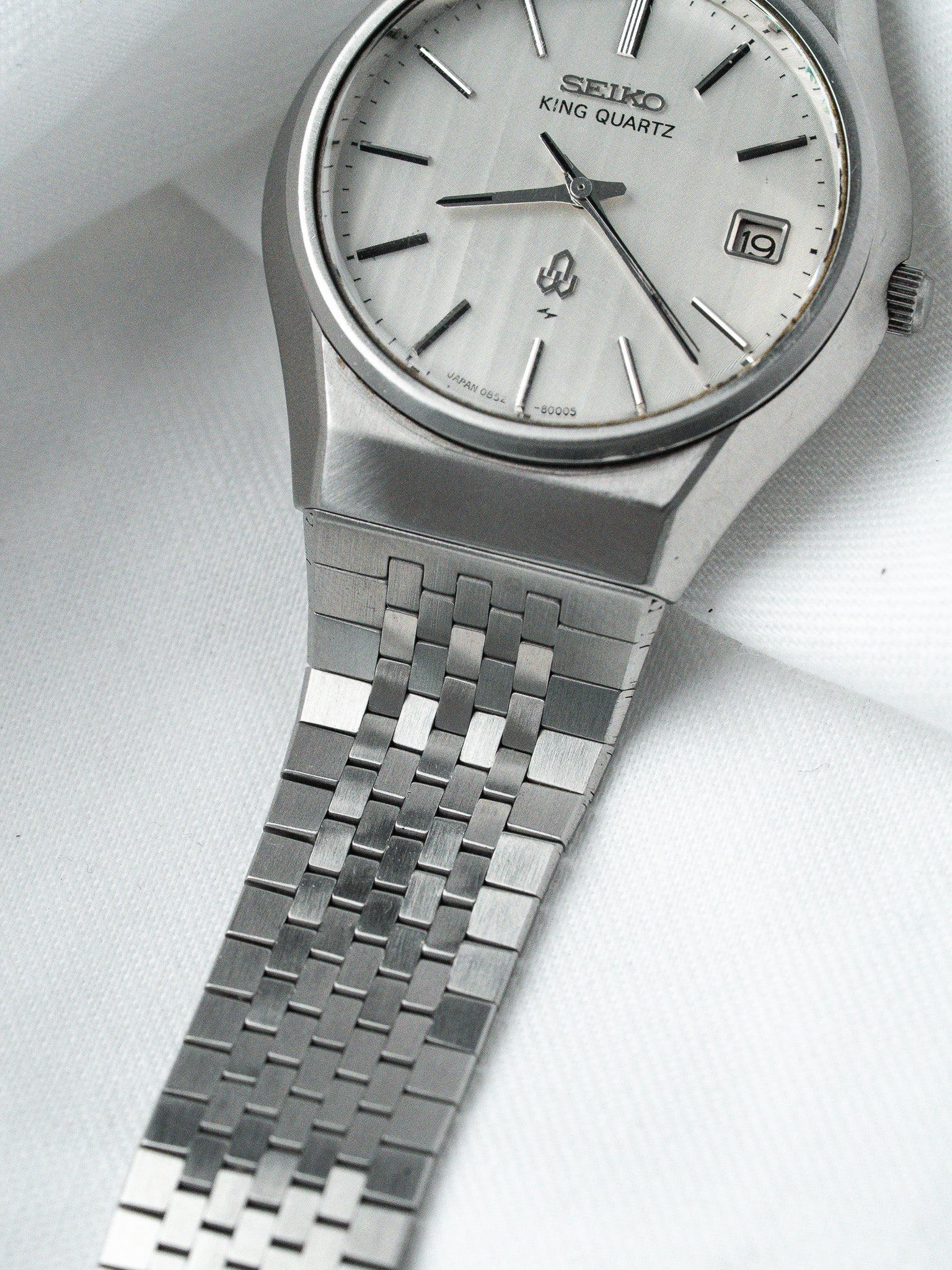 Seiko King Quartz vintage watch with silver dial and metal bracelet on white fabric
