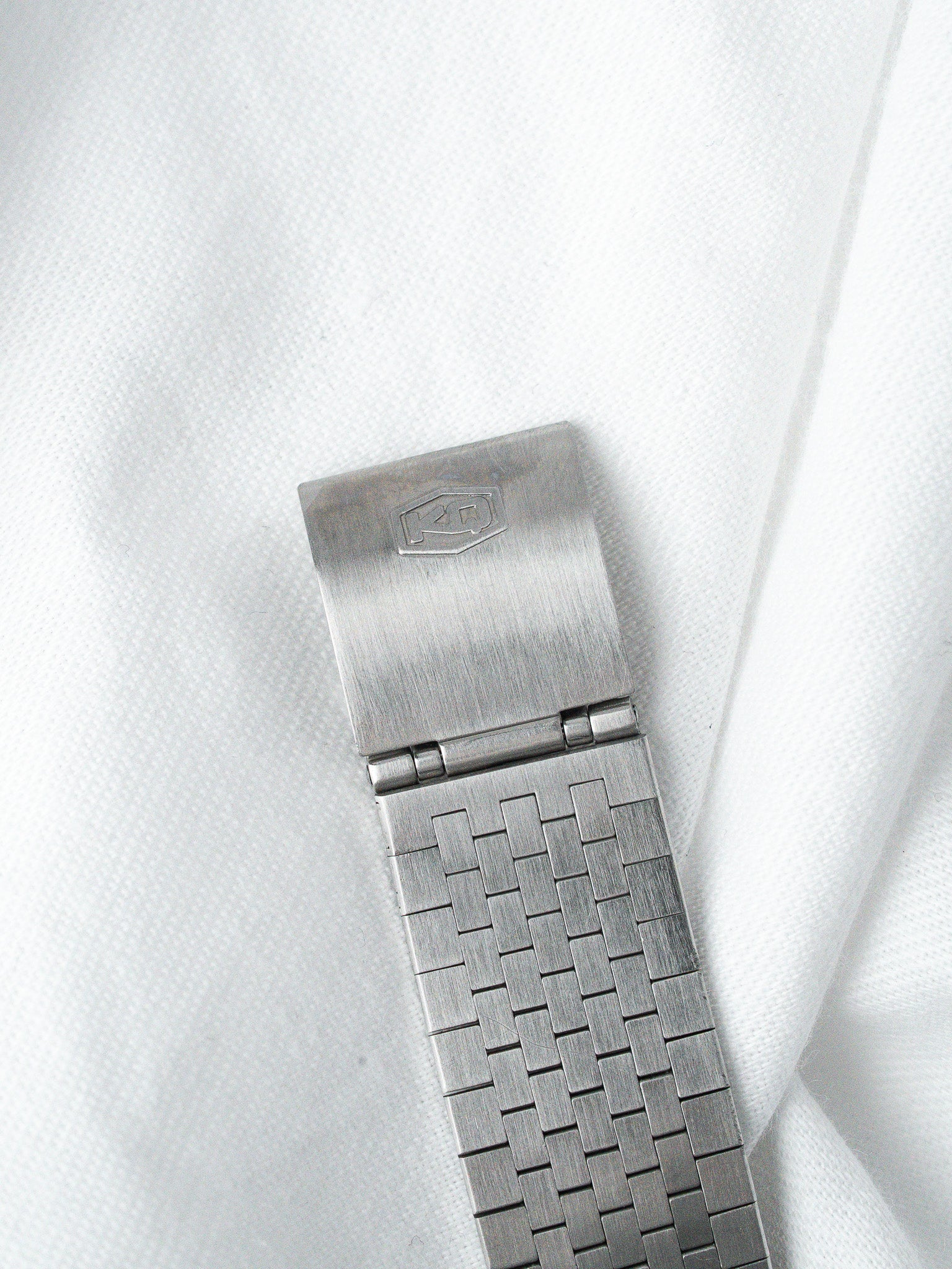 Vintage Rolex Oyster bracelet with woven link design and signed clasp on white fabric