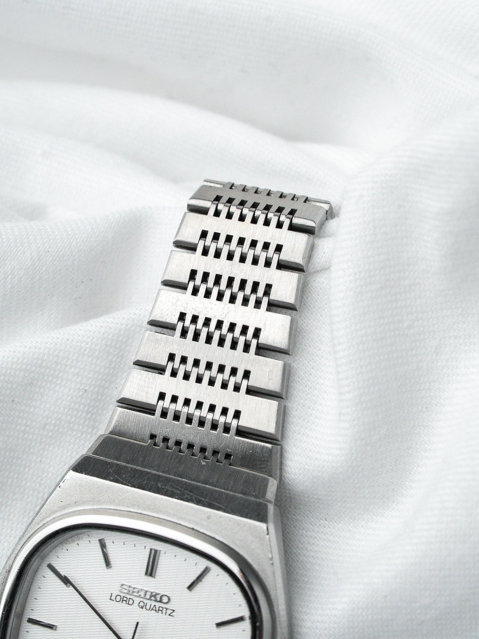 Seiko Lord Quartz vintage watch with silver dial and textured metal bracelet on white fabric
