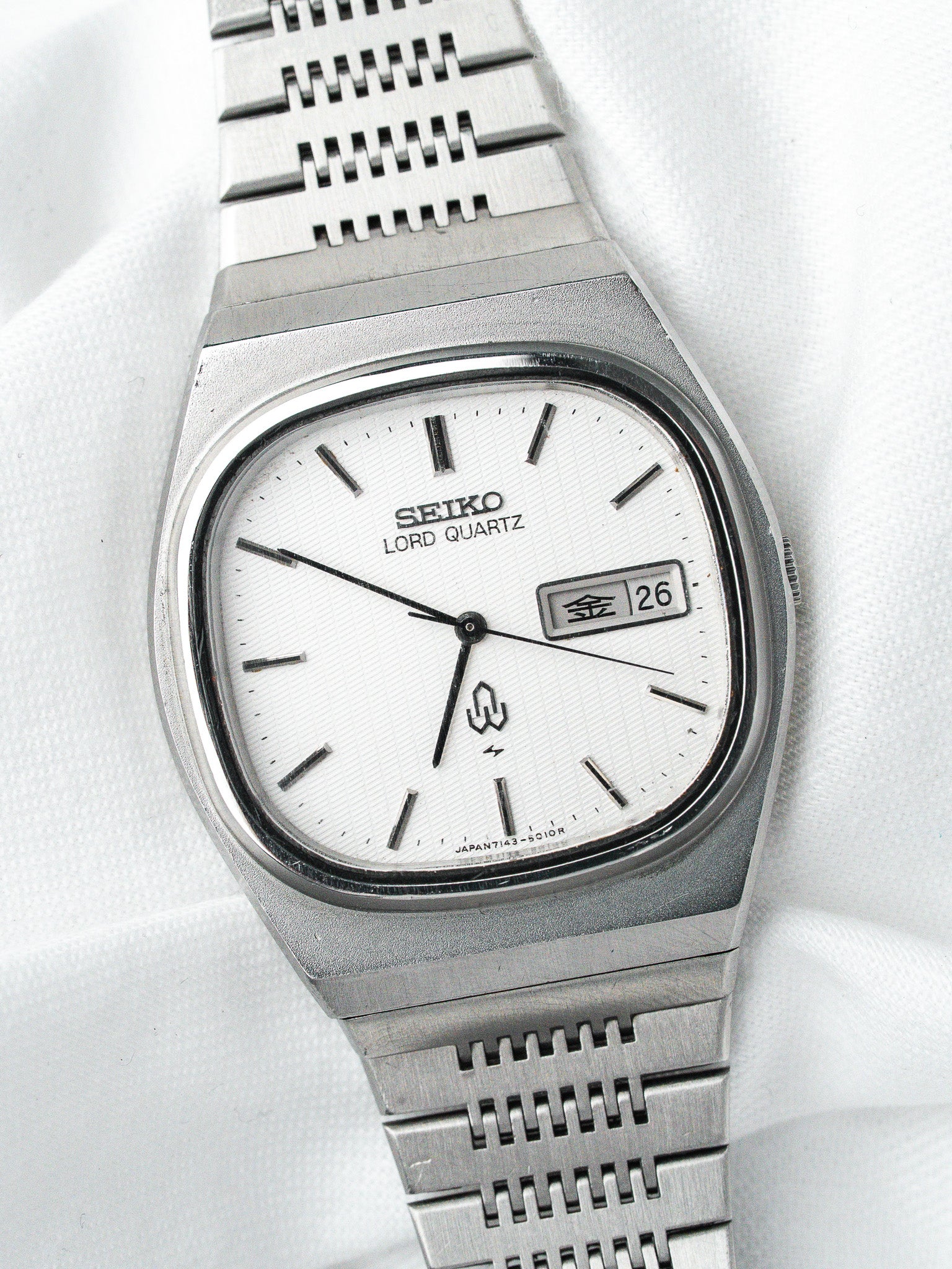Seiko Lord Quartz vintage watch with white dial, steel case, and textured bracelet on white fabric