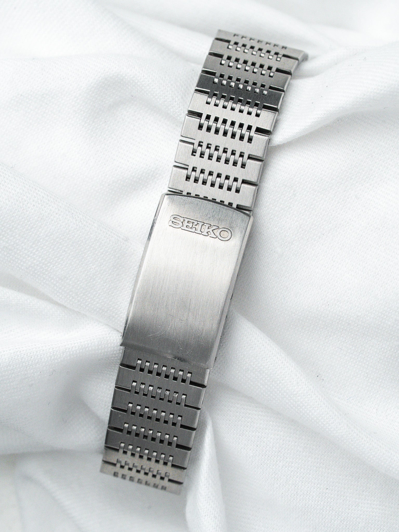 Seiko vintage steel watch bracelet with mesh links on white fabric