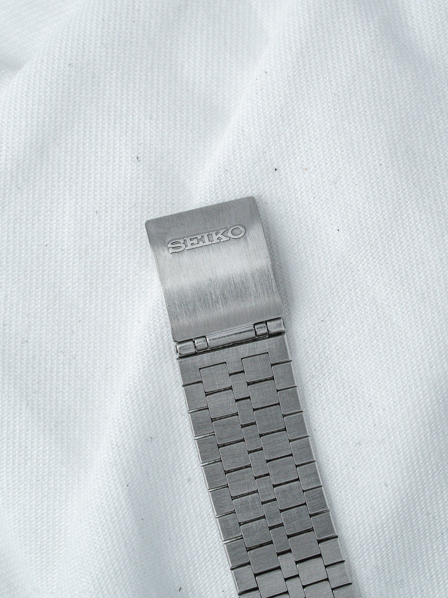 Seiko vintage watch bracelet with brushed metal links on white fabric