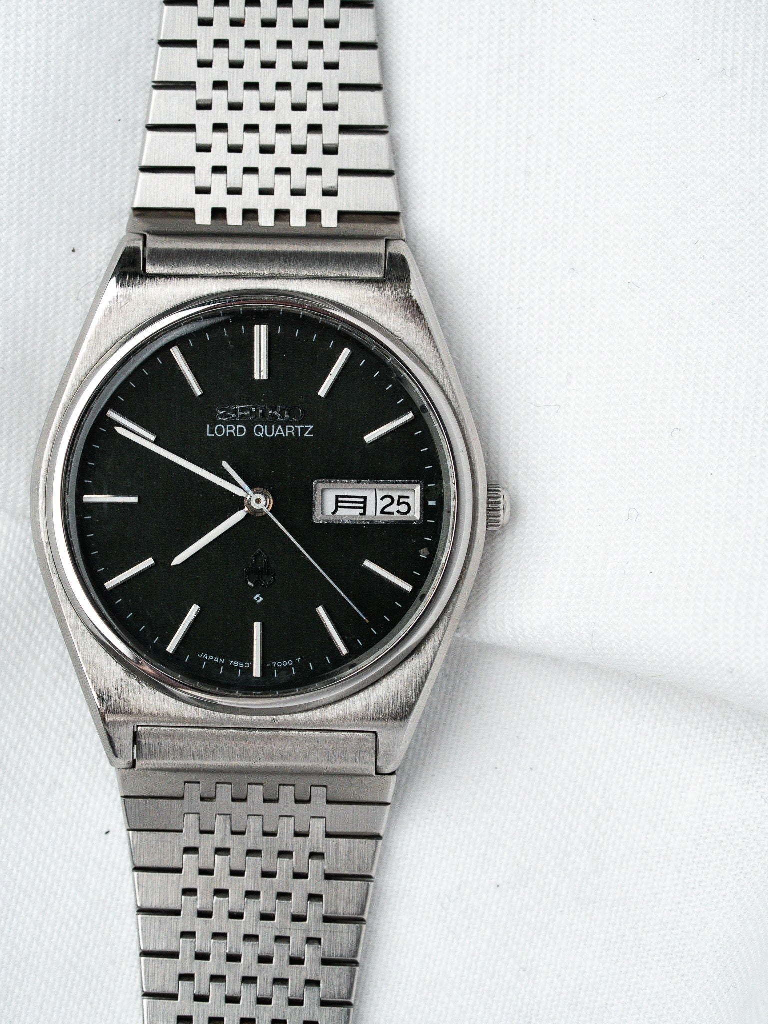 Seiko Lord Quartz vintage watch with black dial, silver markers, and mesh bracelet on white background