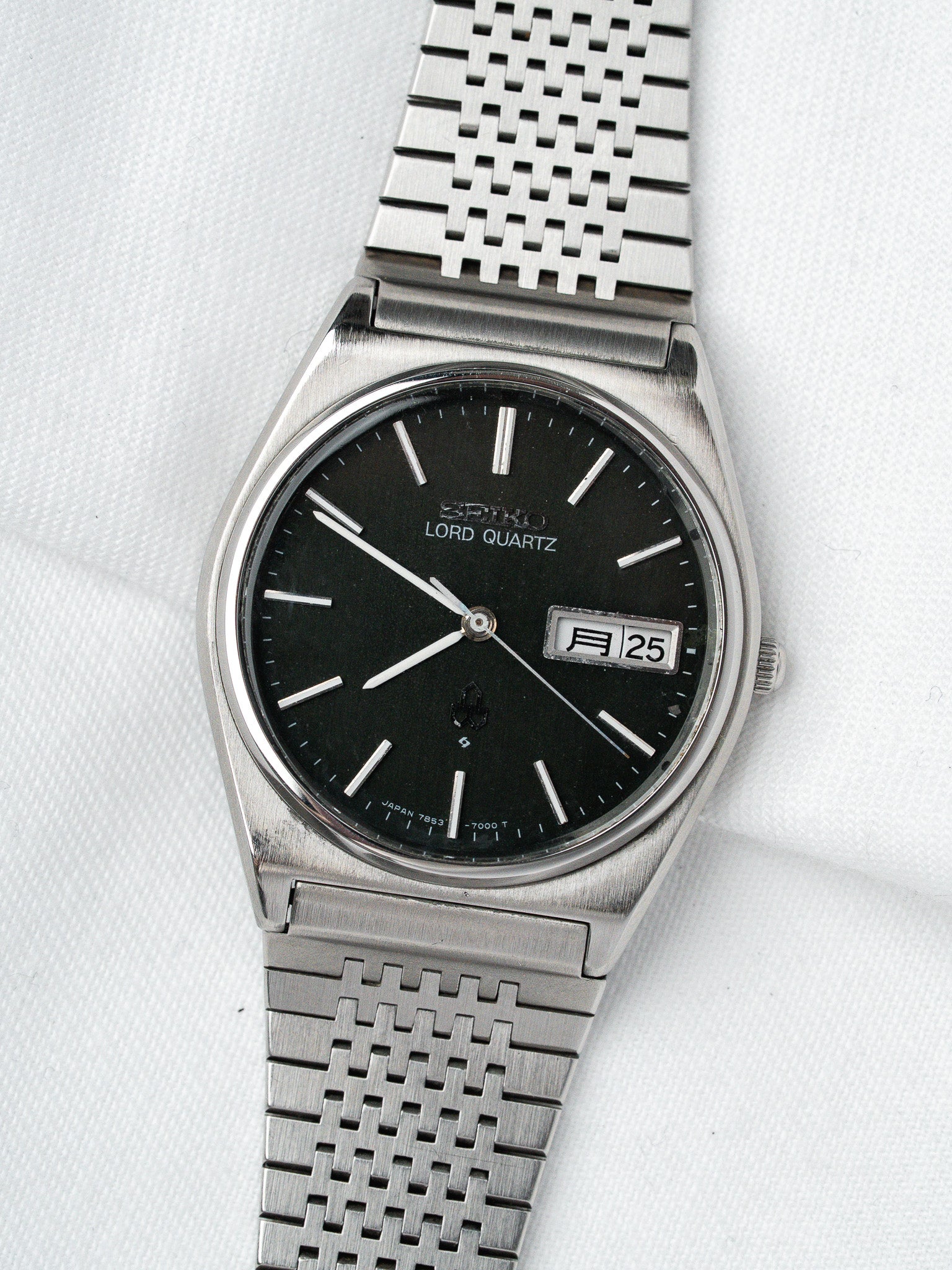 Seiko Lord Quartz vintage watch with black dial, silver markers, and mesh bracelet on white background