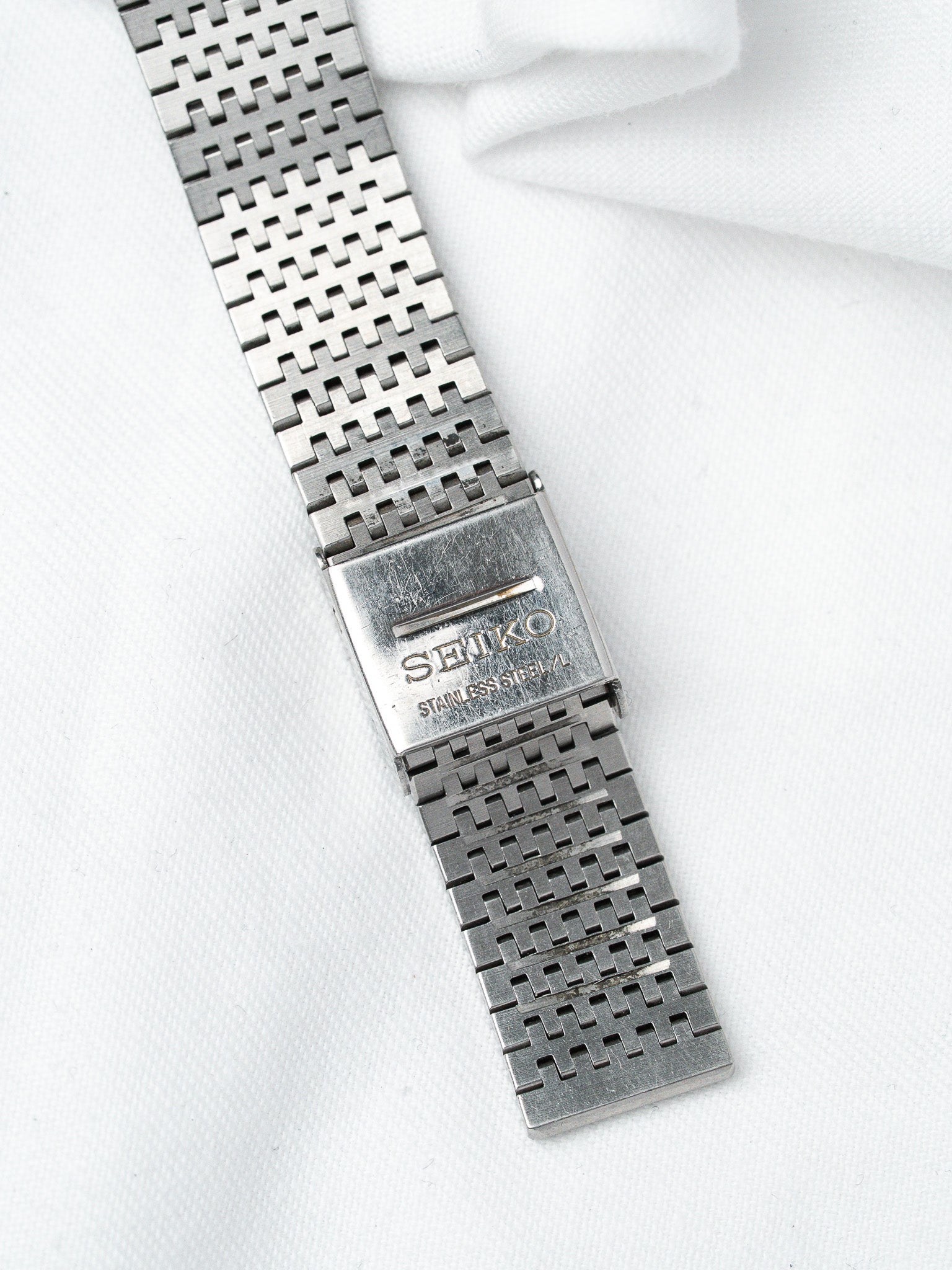 Seiko vintage stainless steel bracelet with textured link design on white fabric