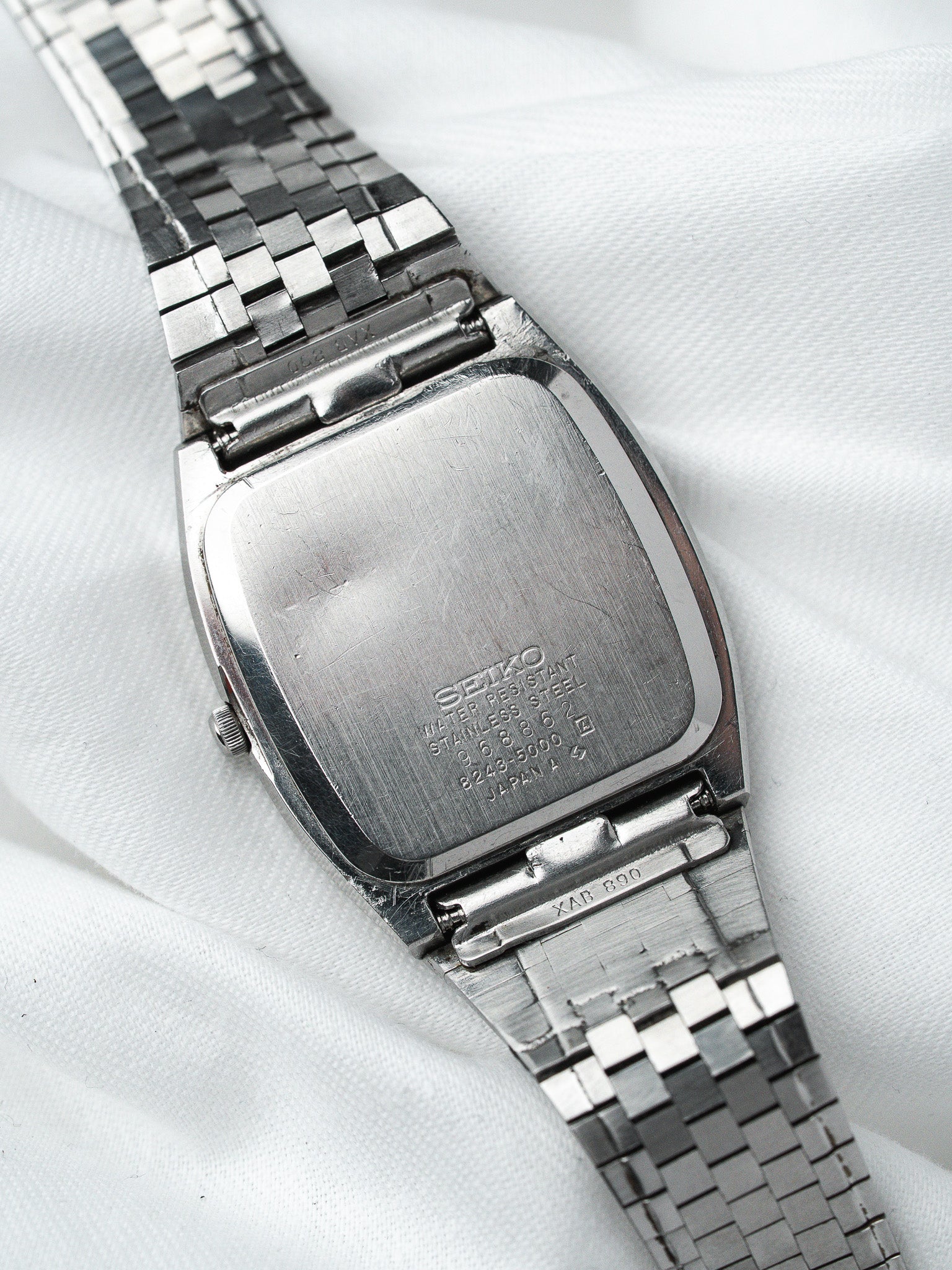 Vintage Seiko watch with stainless steel case and bracelet, back view on white fabric