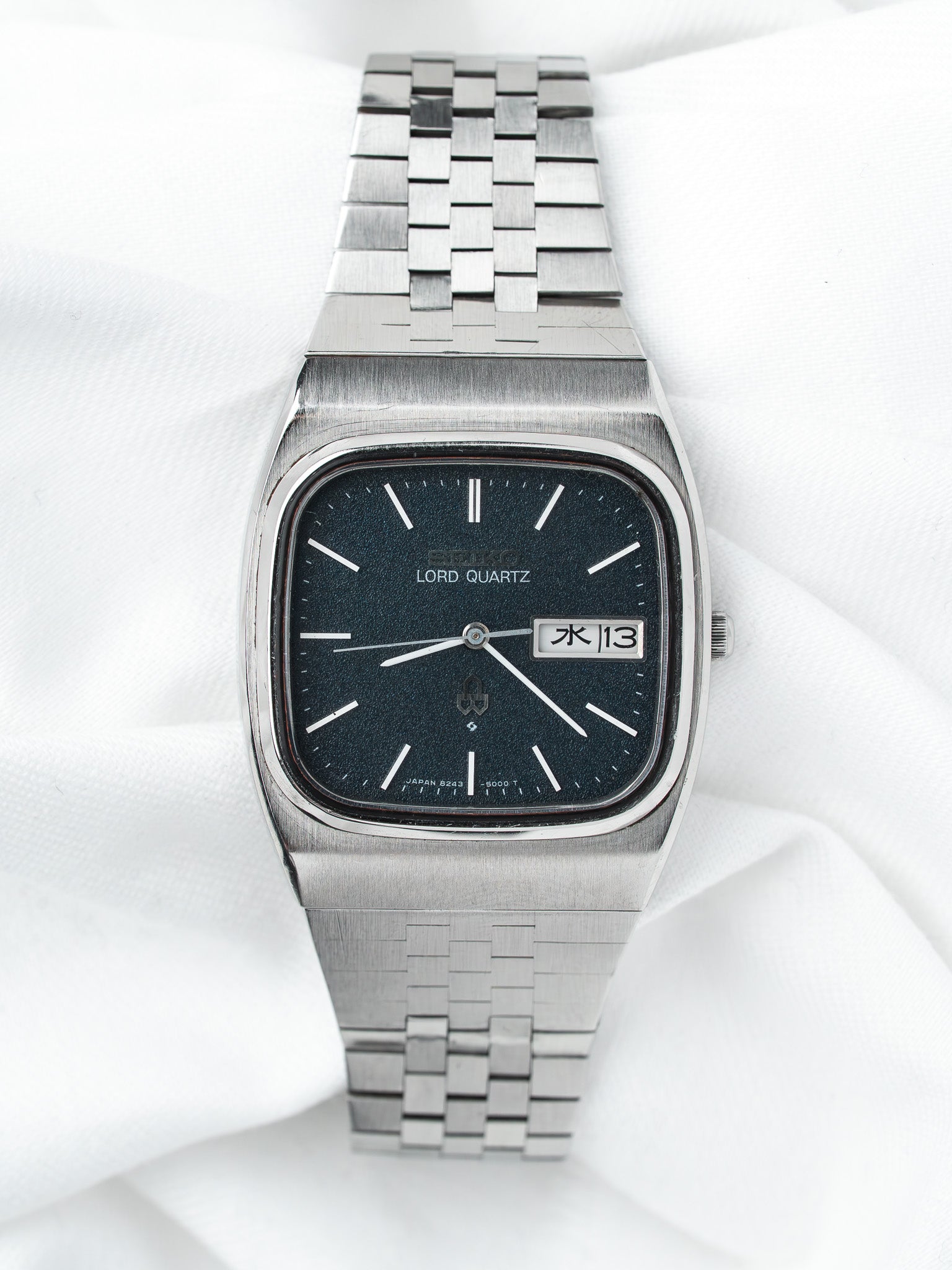 Seiko Lord Quartz vintage watch with black dial, steel bracelet, day-date display on white fabric