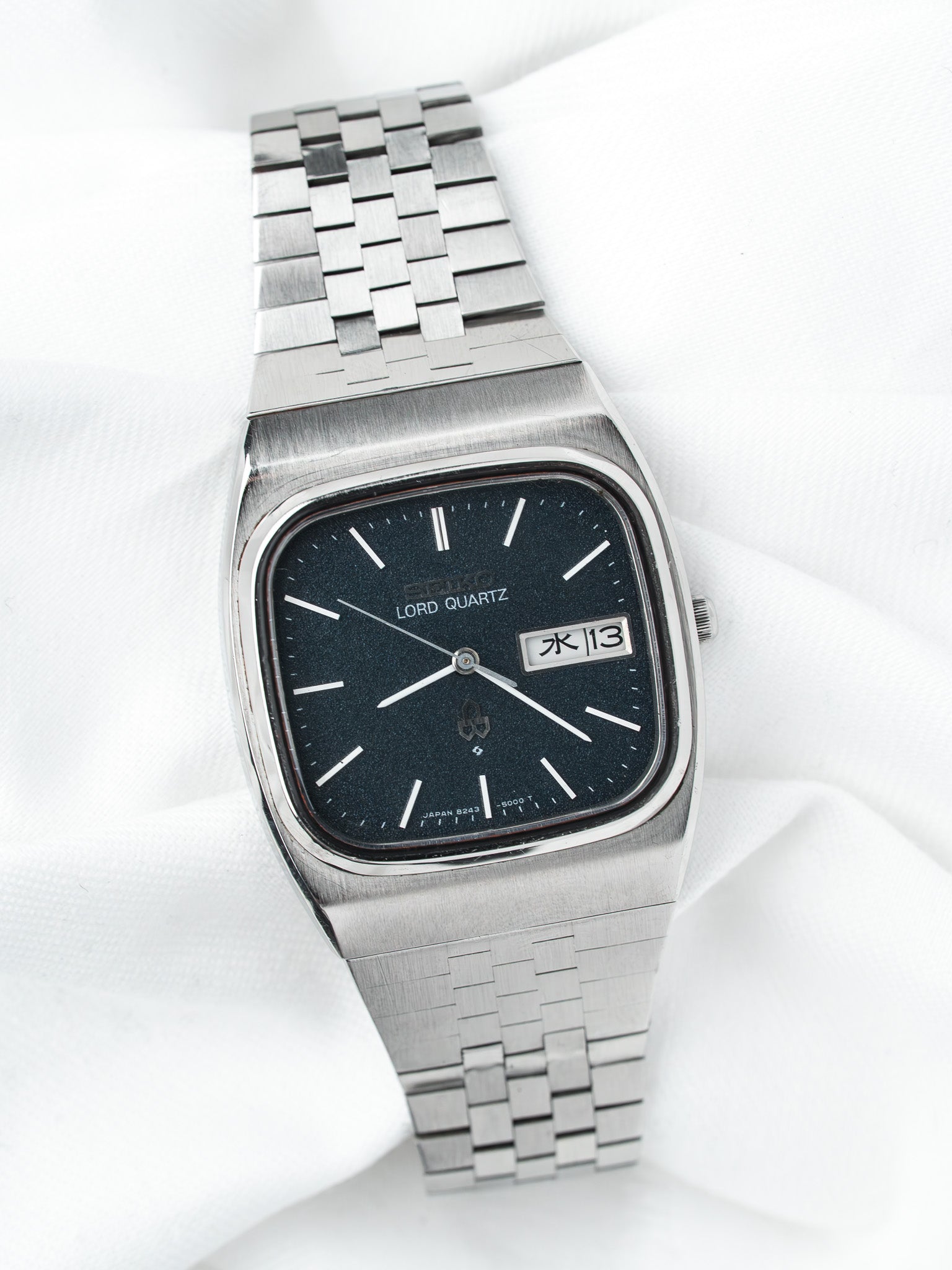Seiko Lord Quartz vintage watch with black dial, steel bracelet, day-date display on white fabric
