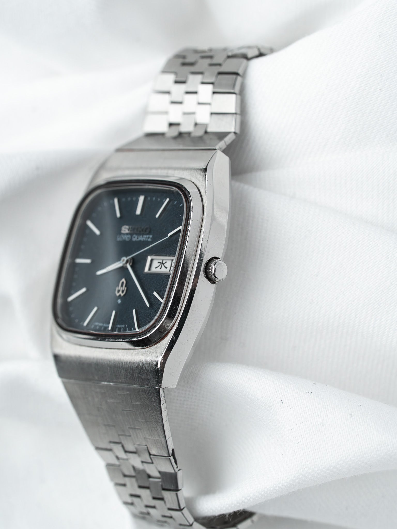 Seiko Lord Quartz vintage watch with black dial and steel bracelet on white fabric