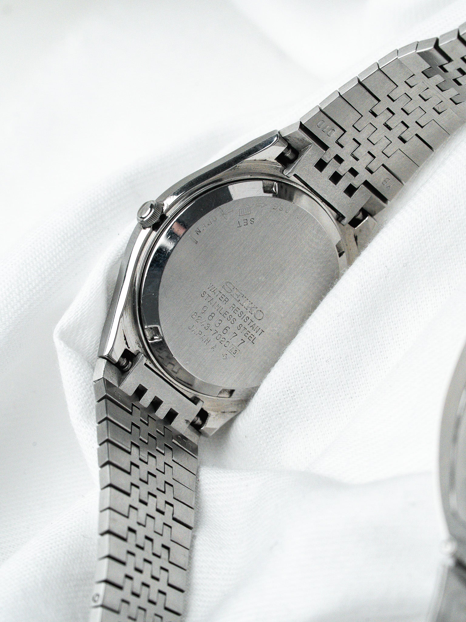 Seiko vintage watch back stainless steel case with textured bracelet on white fabric