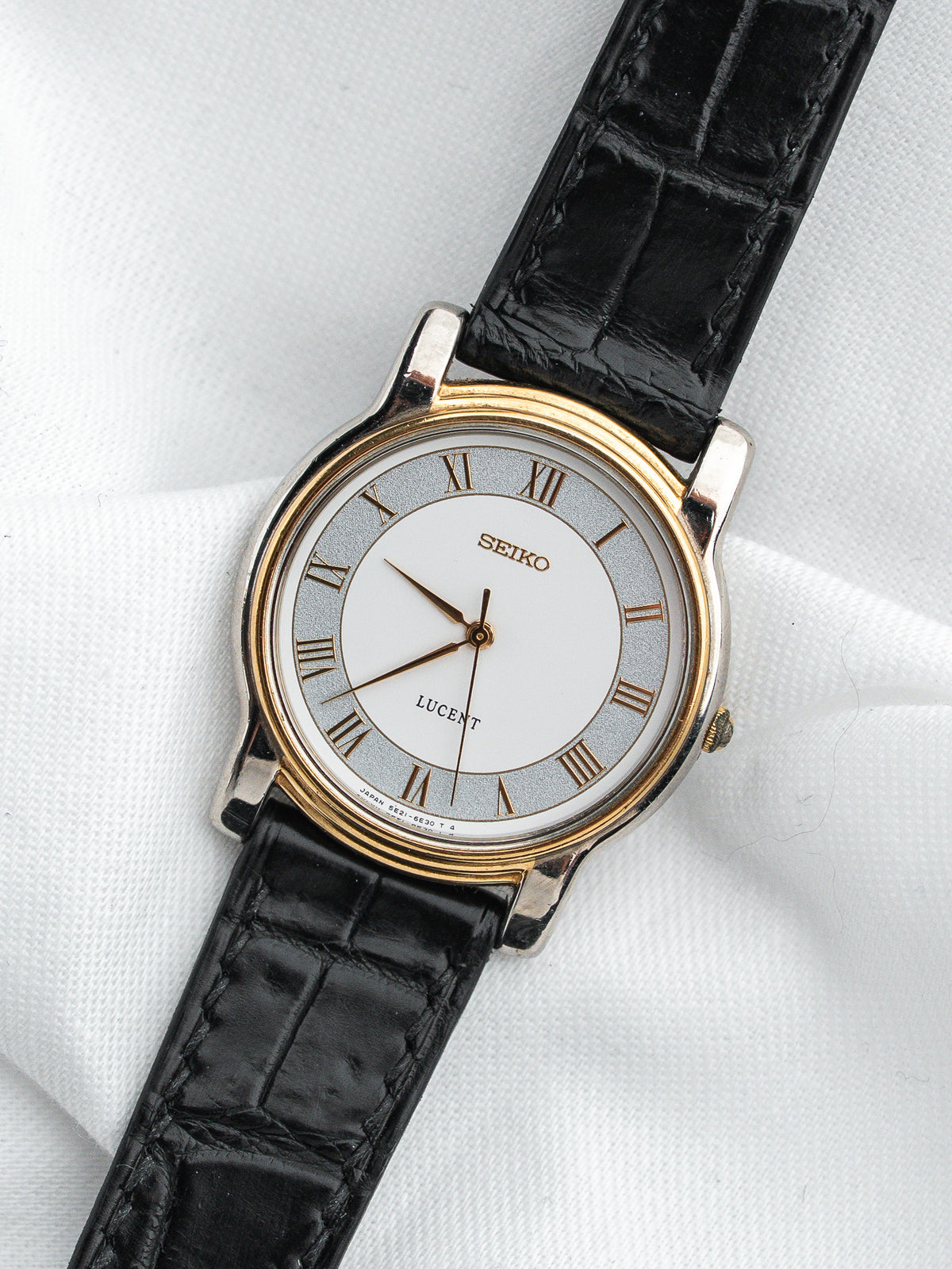 Montre Seiko Lucent avec cadran blanc, index romains et bracelet en cuir noir.