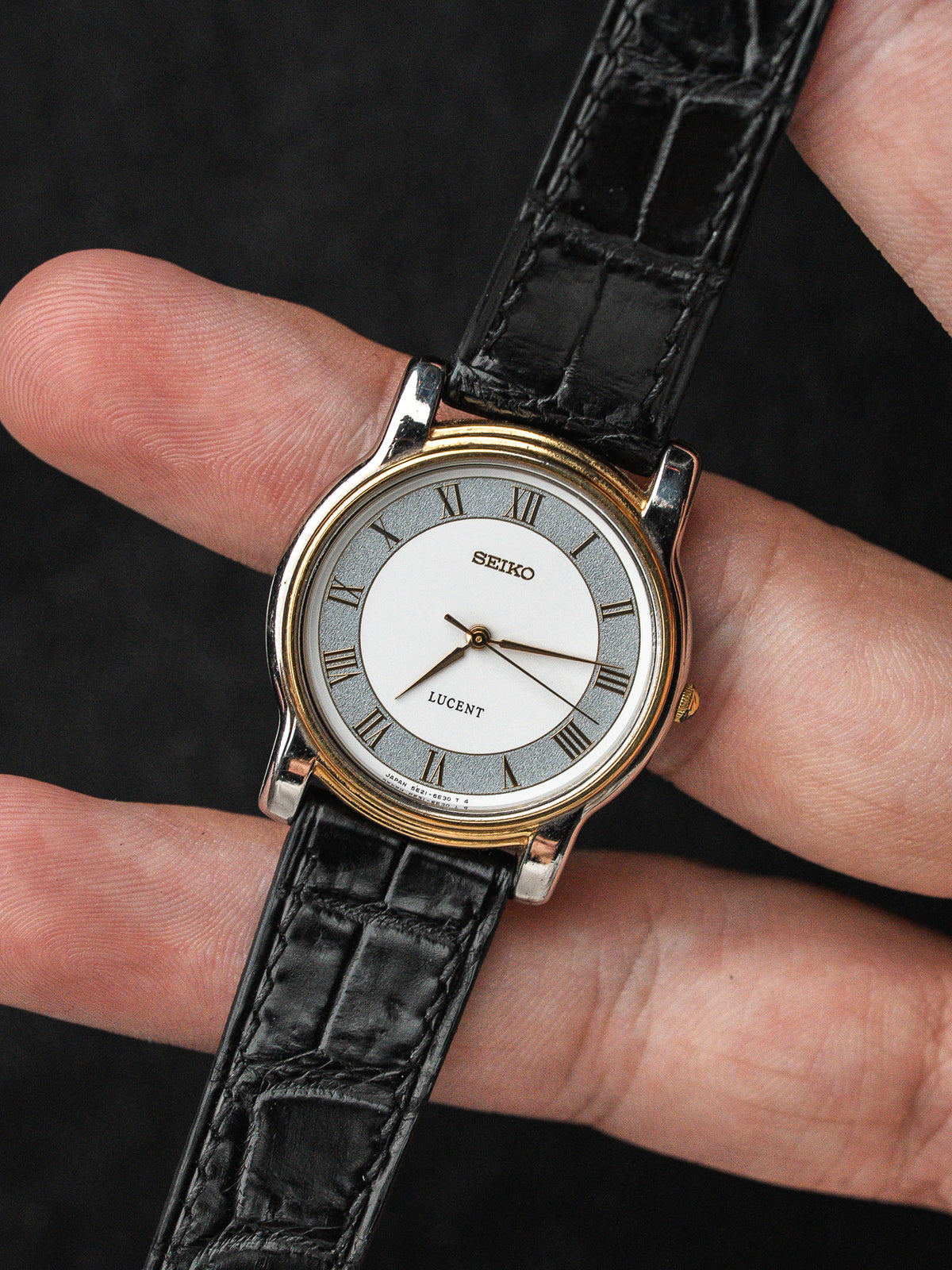 Montre Seiko Lucent vintage avec cadran blanc, chiffres romains et bracelet en cuir noir.