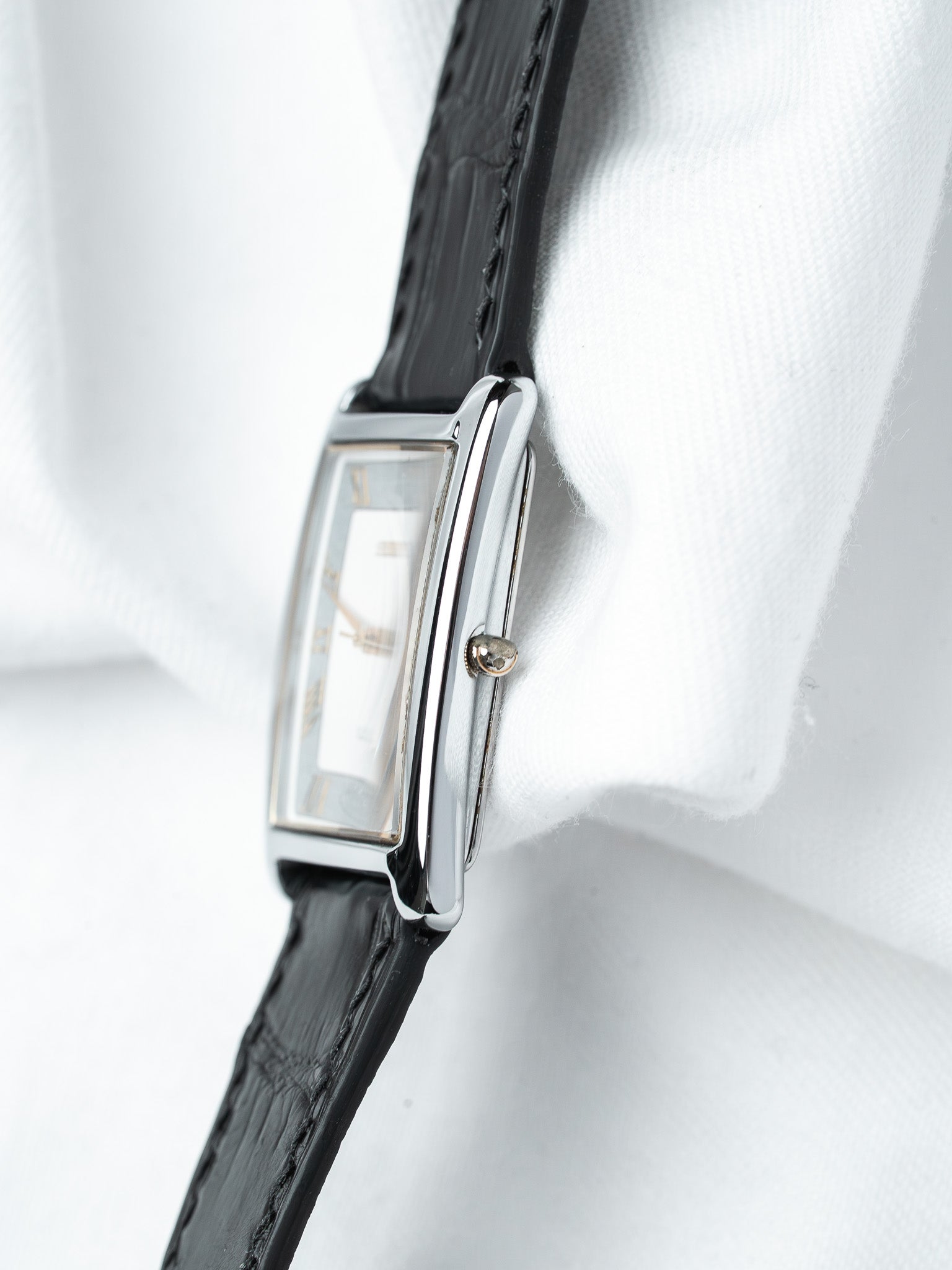 Cartier Tank watch with rectangular steel case, white dial, black leather strap on white fabric