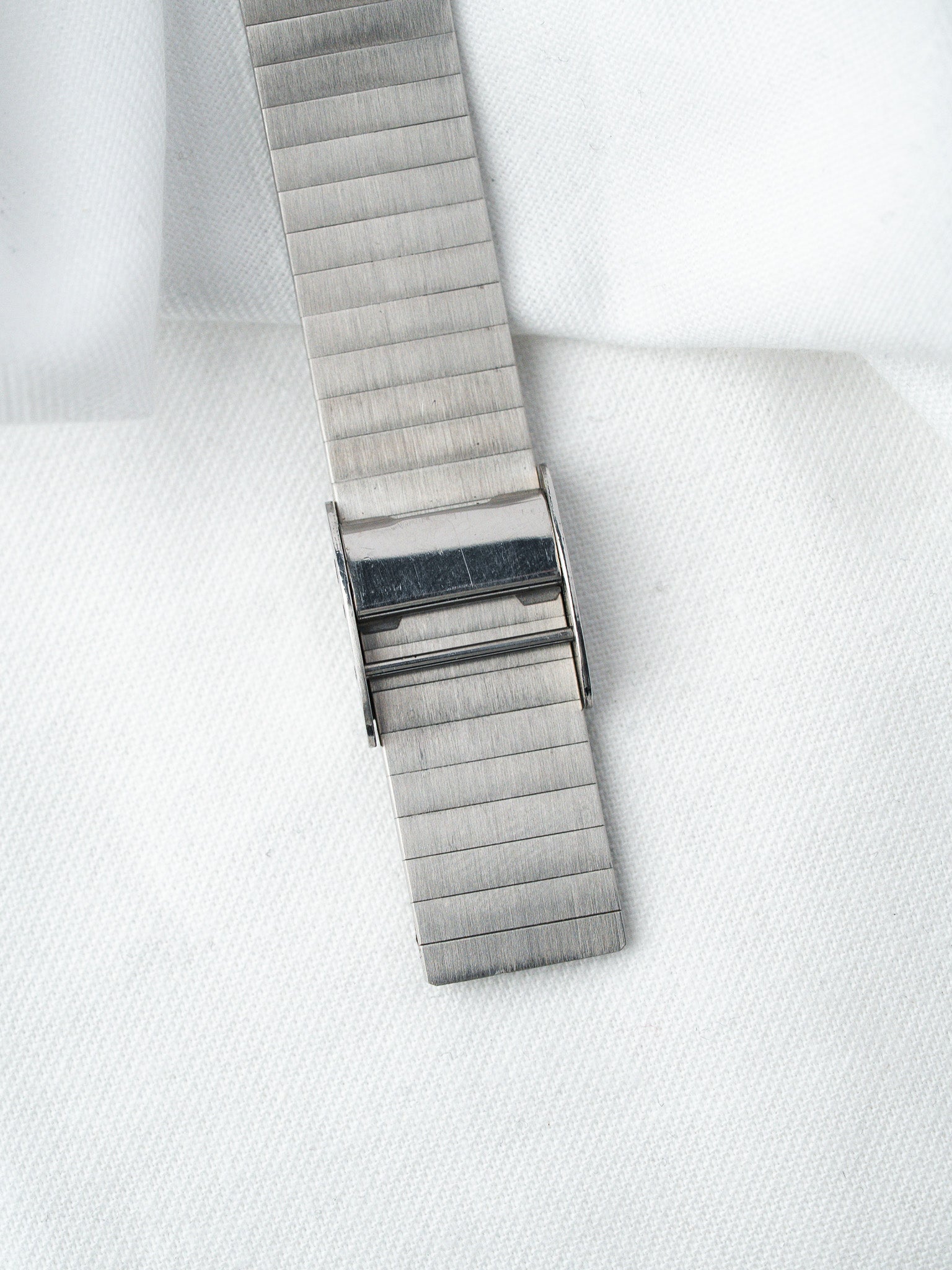 Vintage Omega watch bracelet in brushed steel with deployant clasp on white fabric