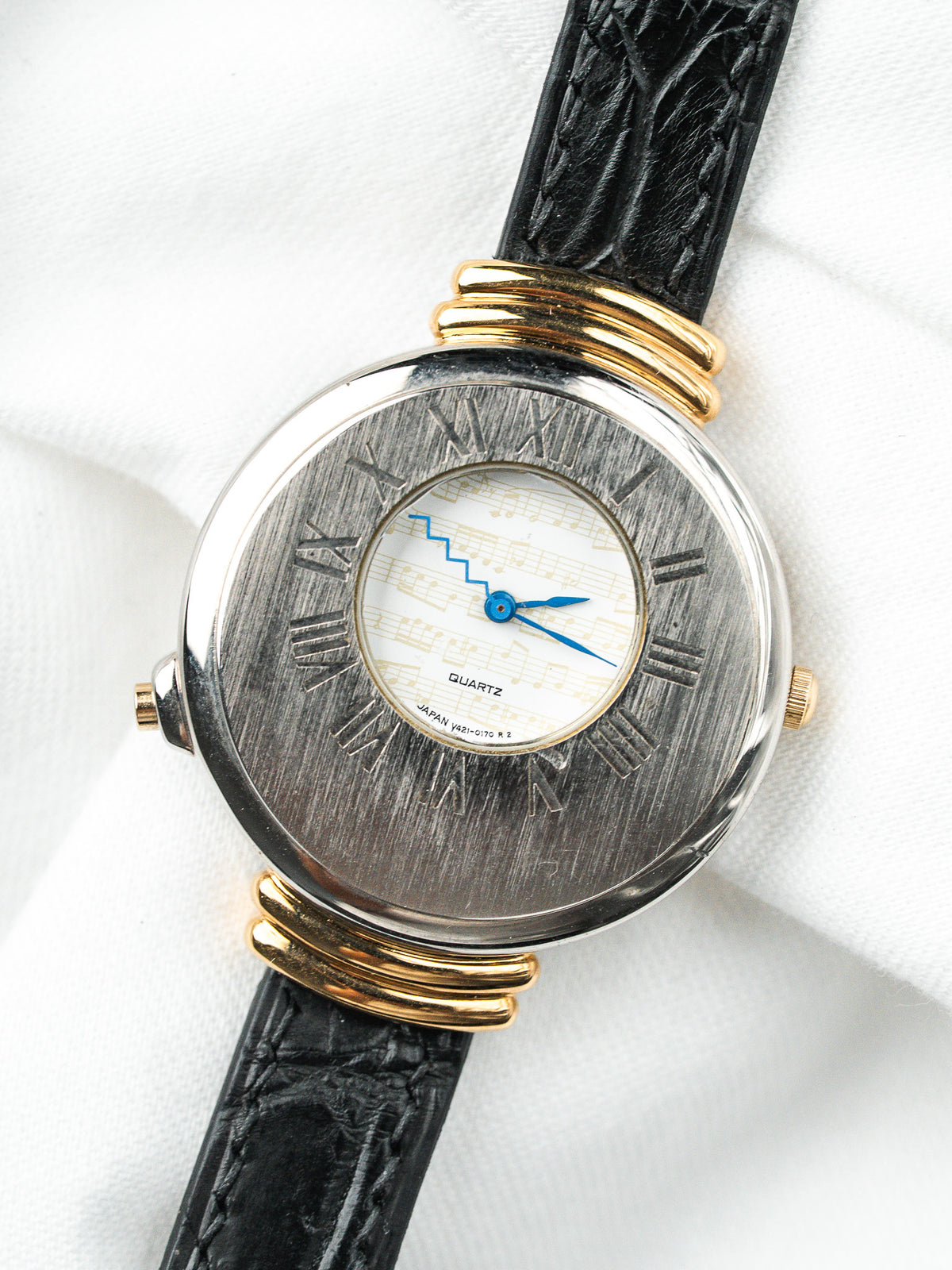 Montre vintage à boîtier rond en acier et or, cadran partition musicale, bracelet cuir noir