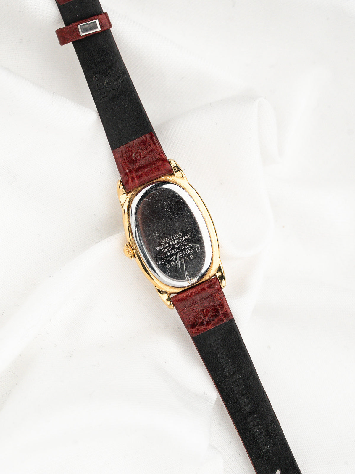 Dos d'une montre vintage Seiko avec bracelet en cuir bicolore noir et rouge.