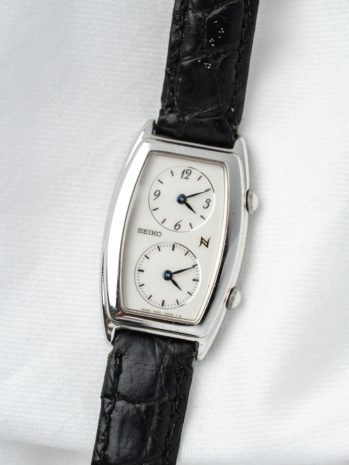 Seiko vintage watch with white dial, black alligator strap, silver case on white background