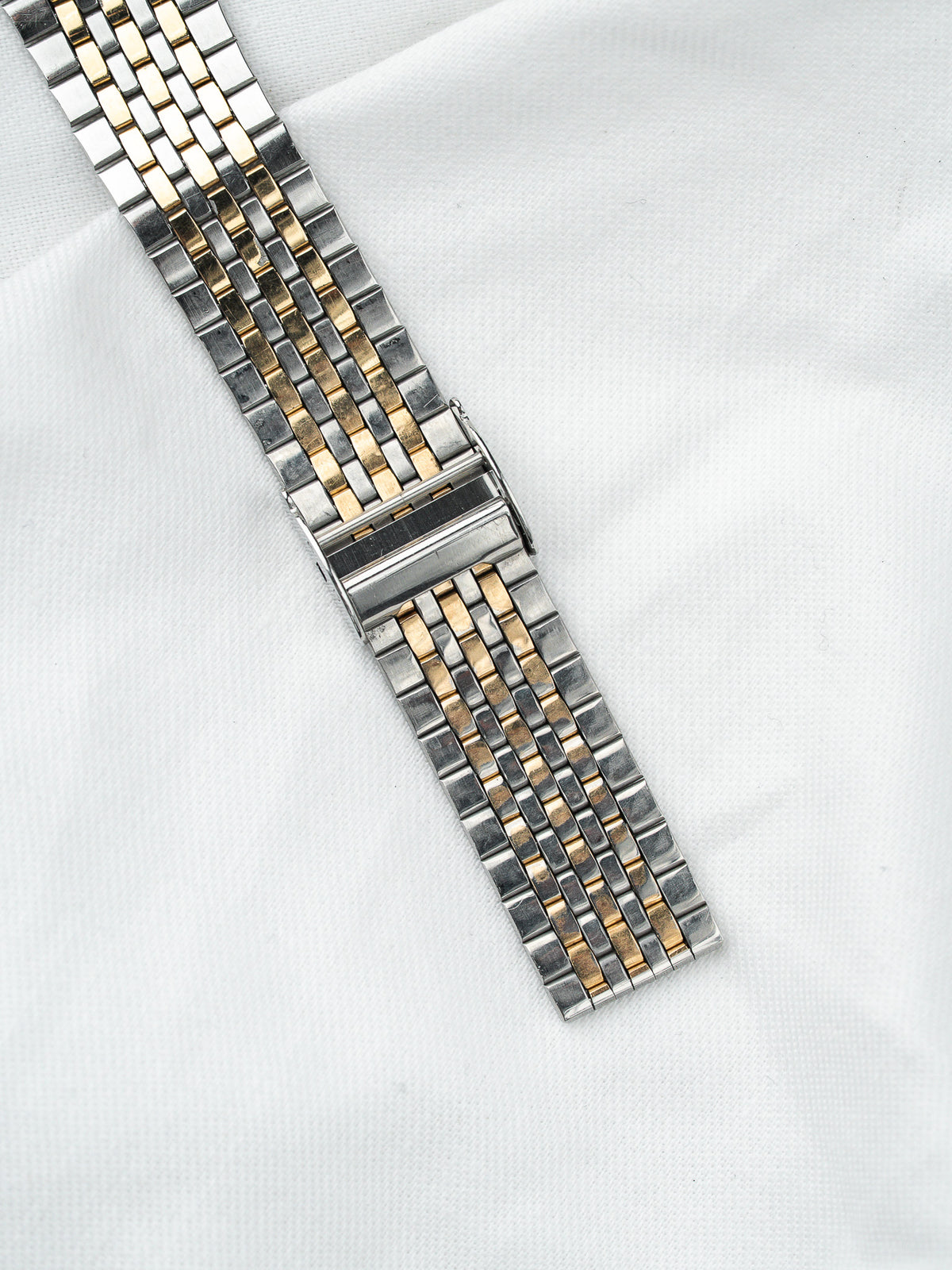 Bracelet de montre vintage en acier et or bicolore sur fond blanc
