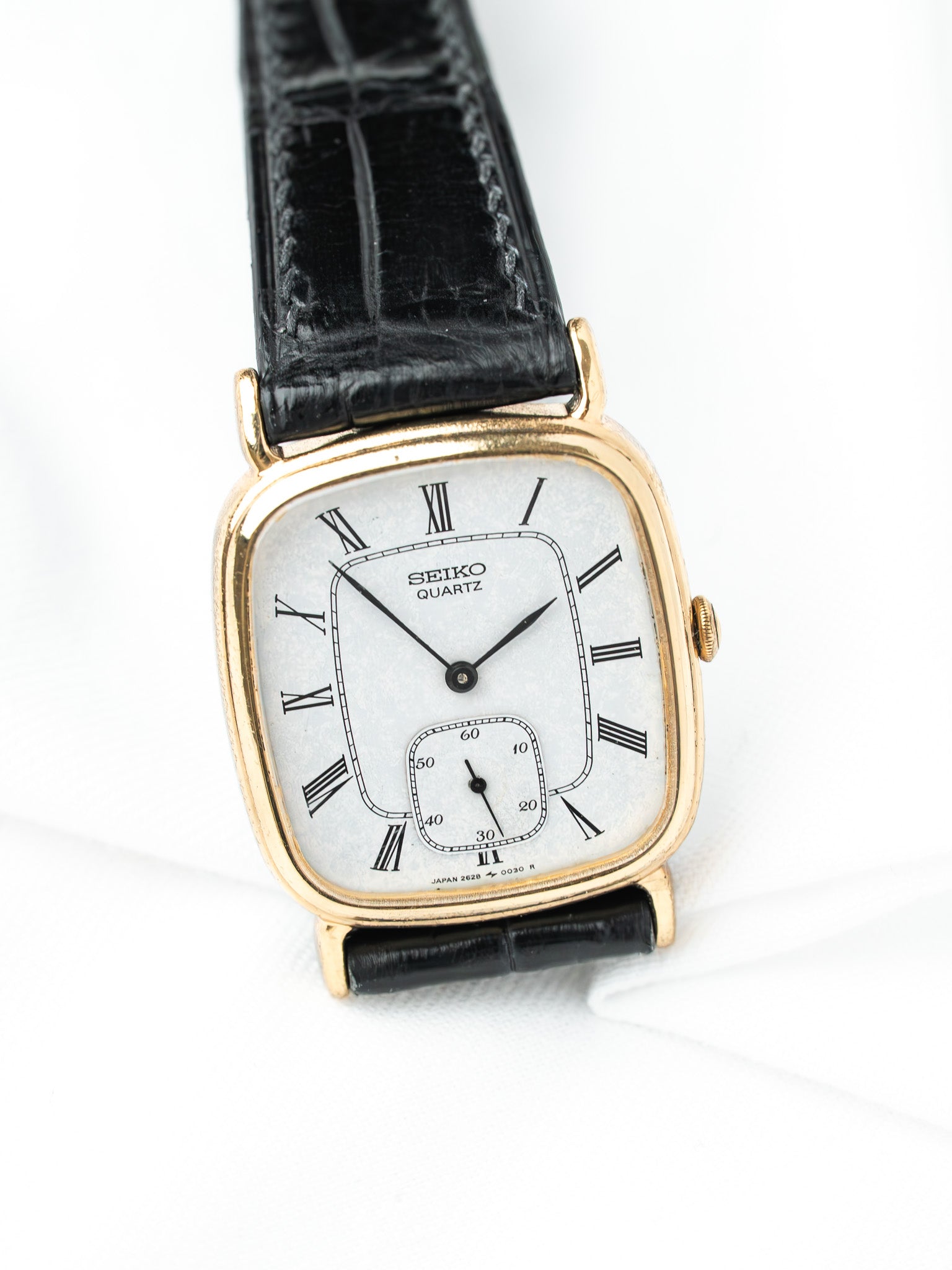 Seiko Quartz vintage watch with gold case, white dial, Roman numerals, black leather strap