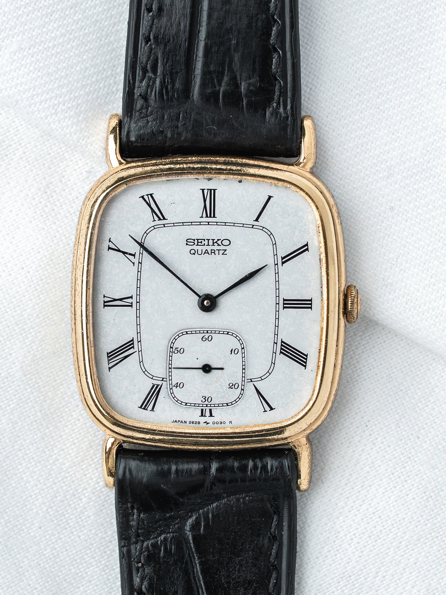 Seiko Quartz vintage watch with gold case, white dial, Roman numerals, black leather strap