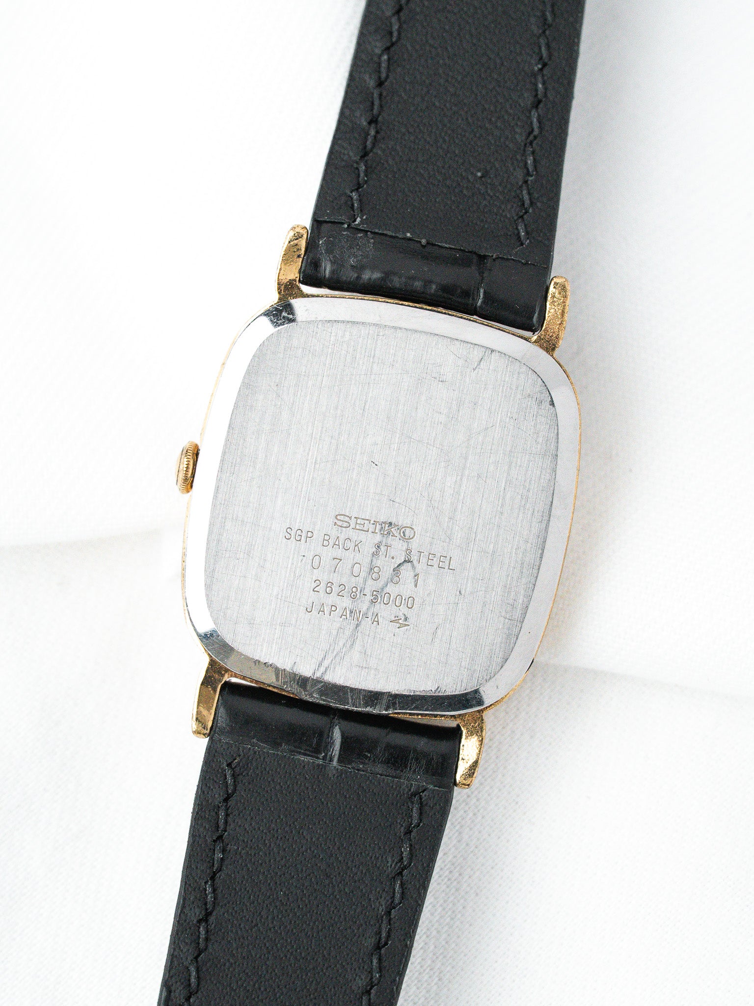 Seiko vintage watch with gold-tone case, black leather strap, steel back engraved