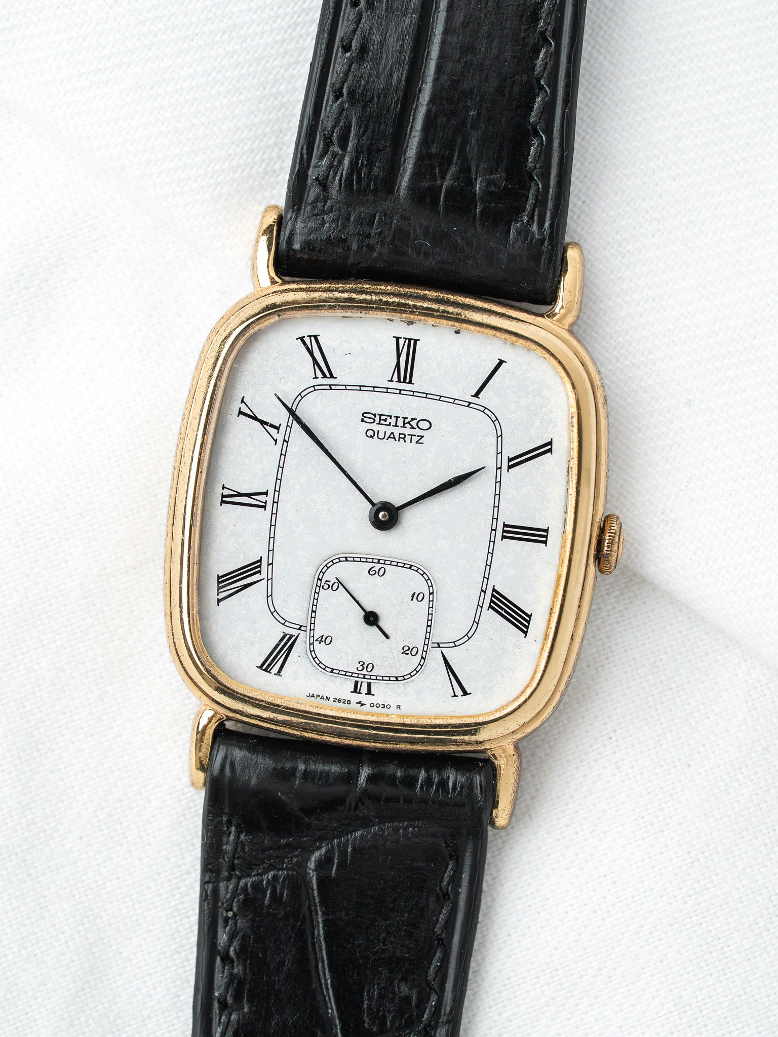 Seiko Quartz vintage watch with gold case, white dial, Roman numerals, black leather strap
